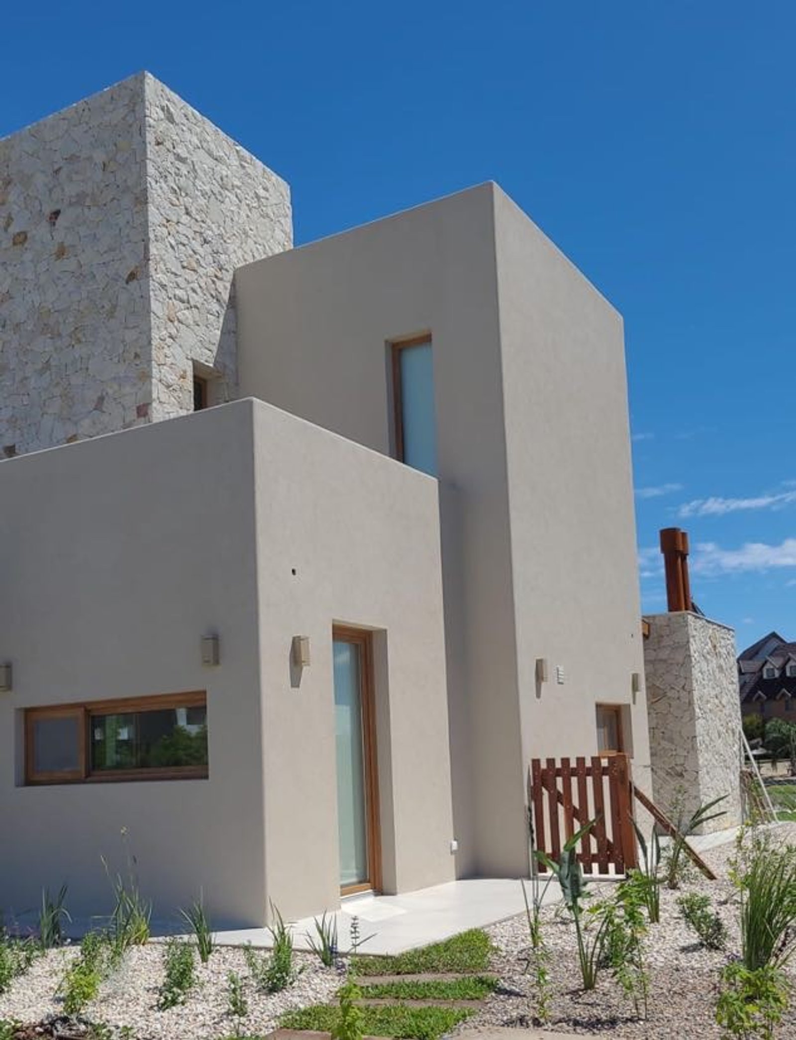 Fachada moderna de casa con contrastes de piedra y revoque — proyecto LOTE 004, por DIKKA Arquitecta , en San Vicente