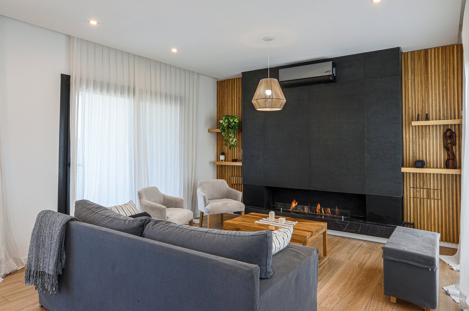 Living moderno con chimenea negra y pared de madera — proyecto SS45, por EZ architects, en Pilar