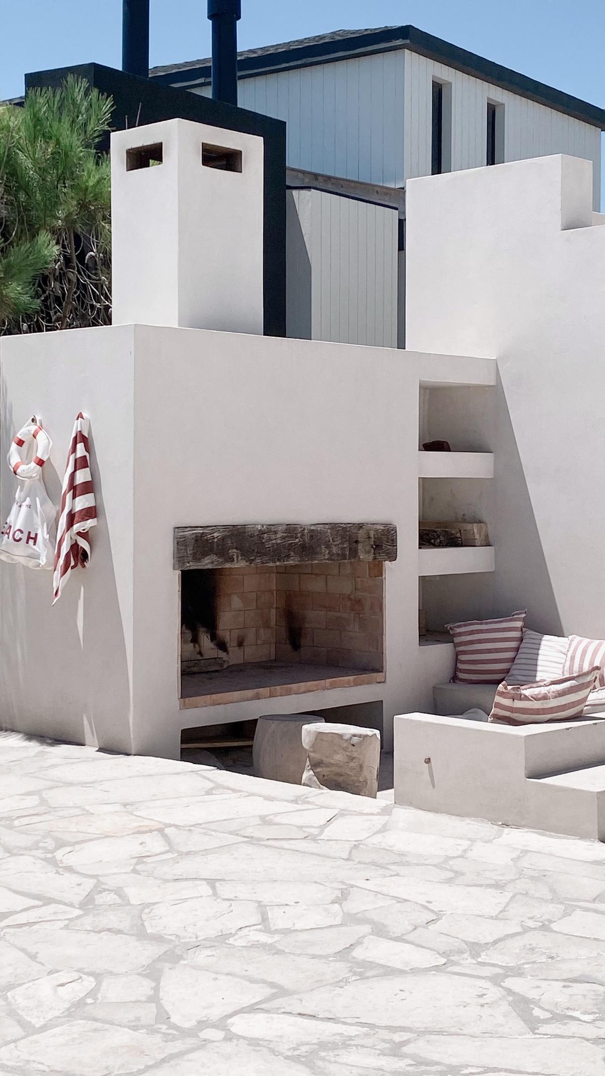Área de churrasqueira mediterrânea com lareira embutida e pátio de pedra — projeto El Refugio, por Grupo Pauta Arquitectura, em Pinamar
