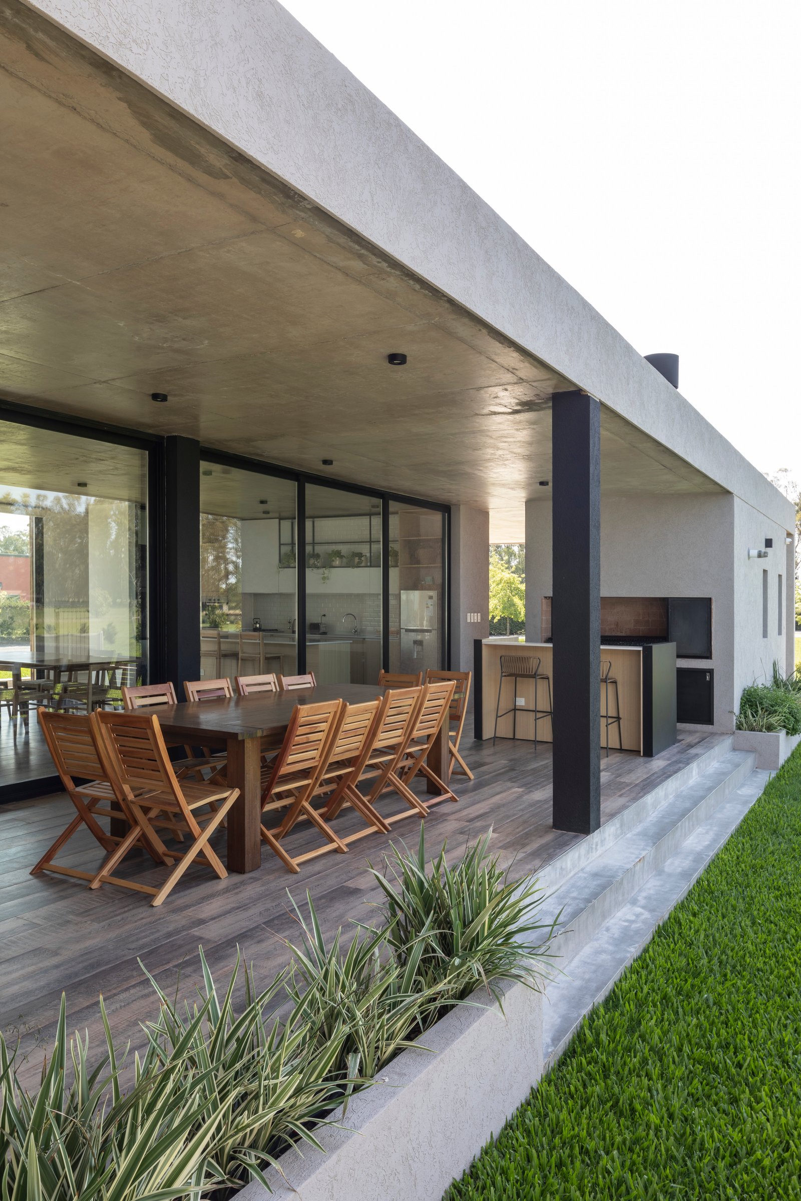 Patio moderno con deck de madera, cocina exterior y techo de hormigón — proyecto Casa Cruz , por Grupo CRBN, en B2812 Exaltación de la Cruz
