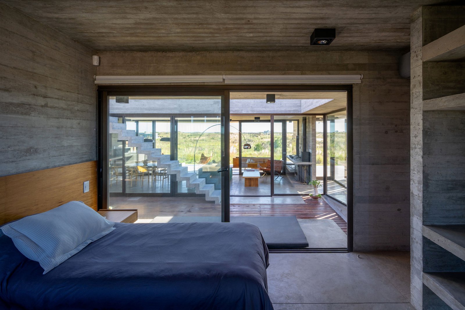 Dormitorio moderno con hormigón visto y vistas al exterior — proyecto Casa Médanos, por Besonías Almeida arquitectos, en JWRC+MQ