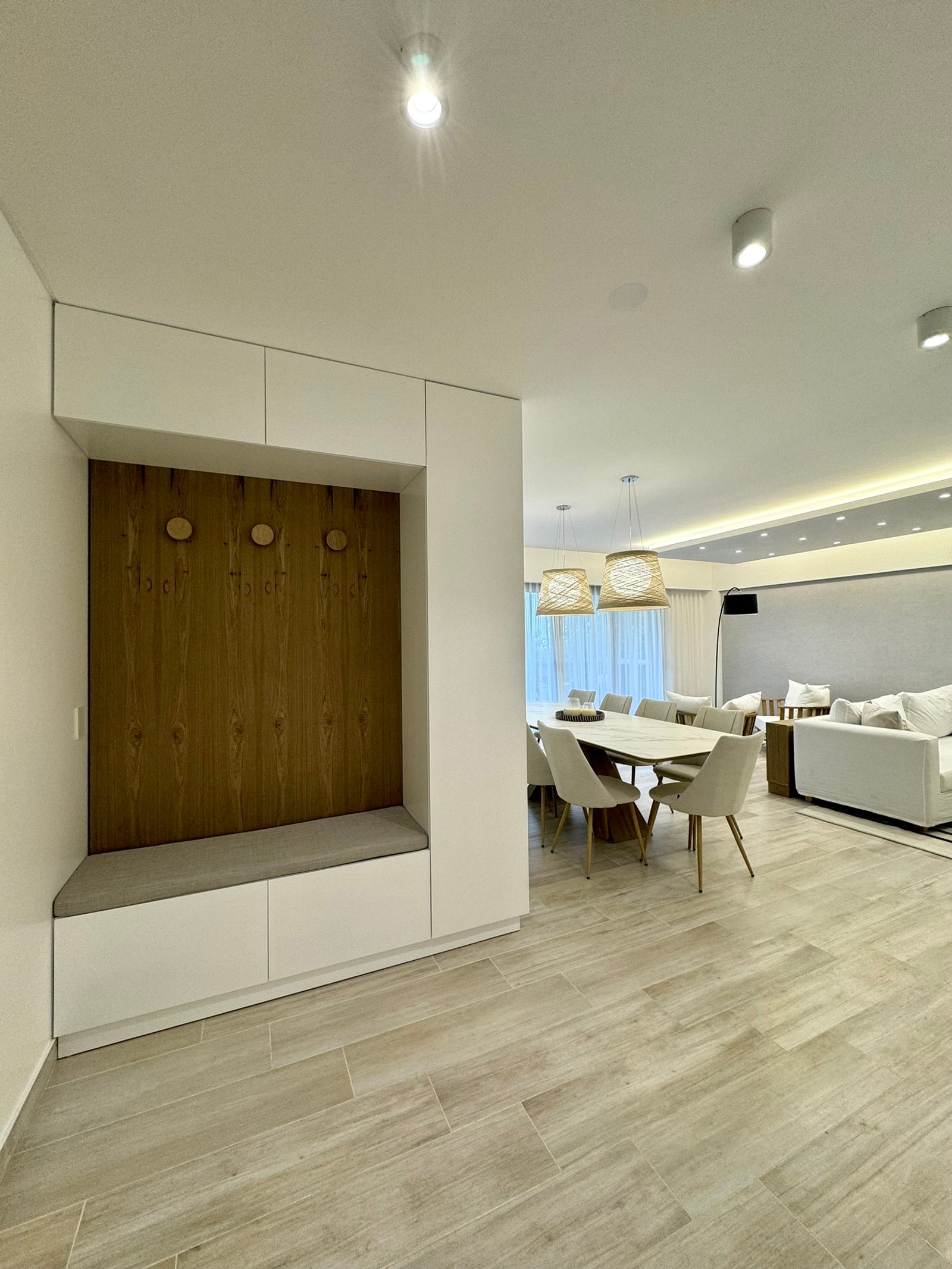 Hall de entrada moderno com banco embutido, sala de jantar e estar integrados — projeto Frias, por MDBK Arquitectura, em Villa Crespo