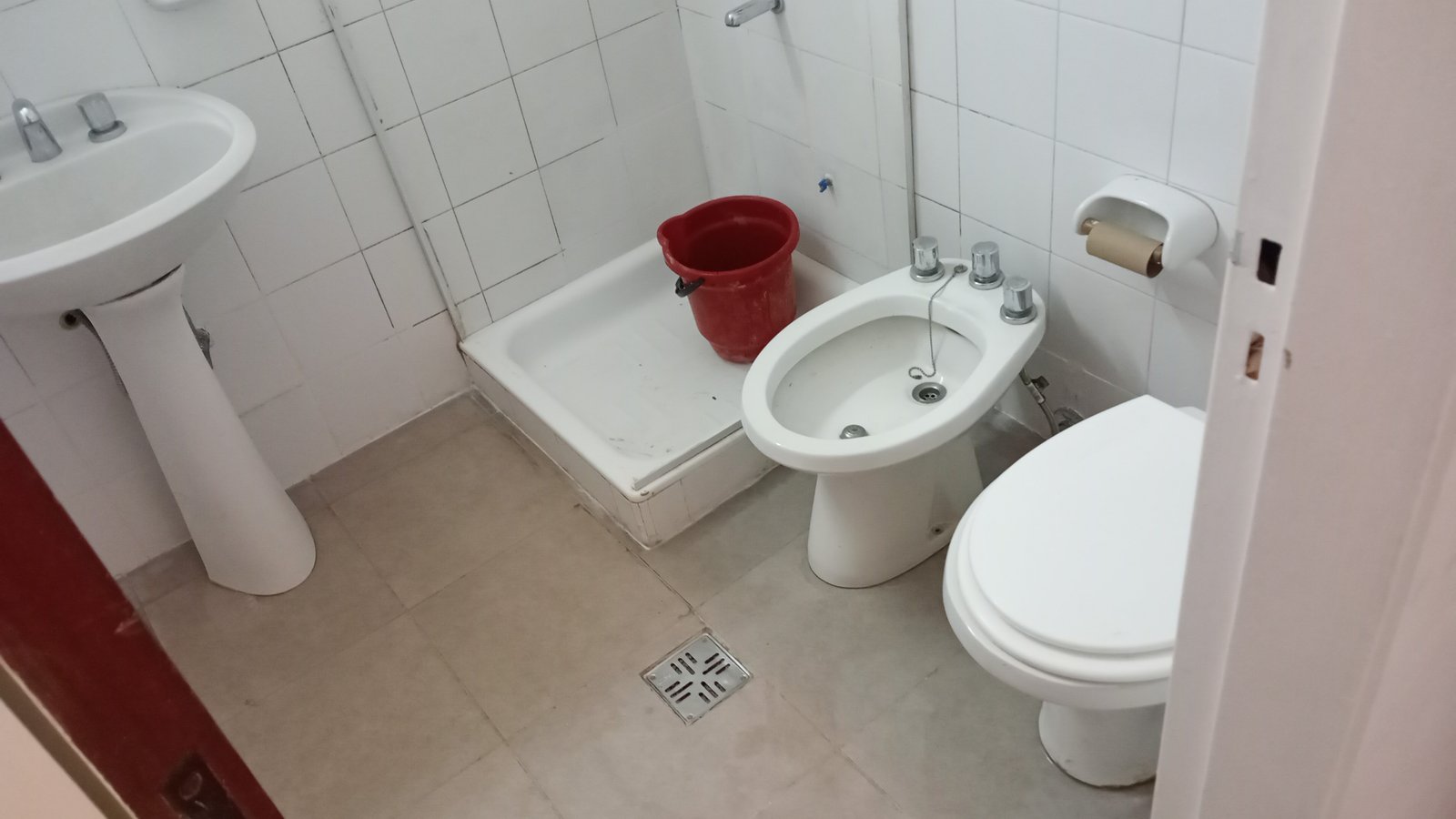 Baño pequeño con lavabo, inodoro, bañera y balde rojo — proyecto Wineberg 2770 , por A&E construcciónes, en Hernan Wineberg 2770 B1636DIE
