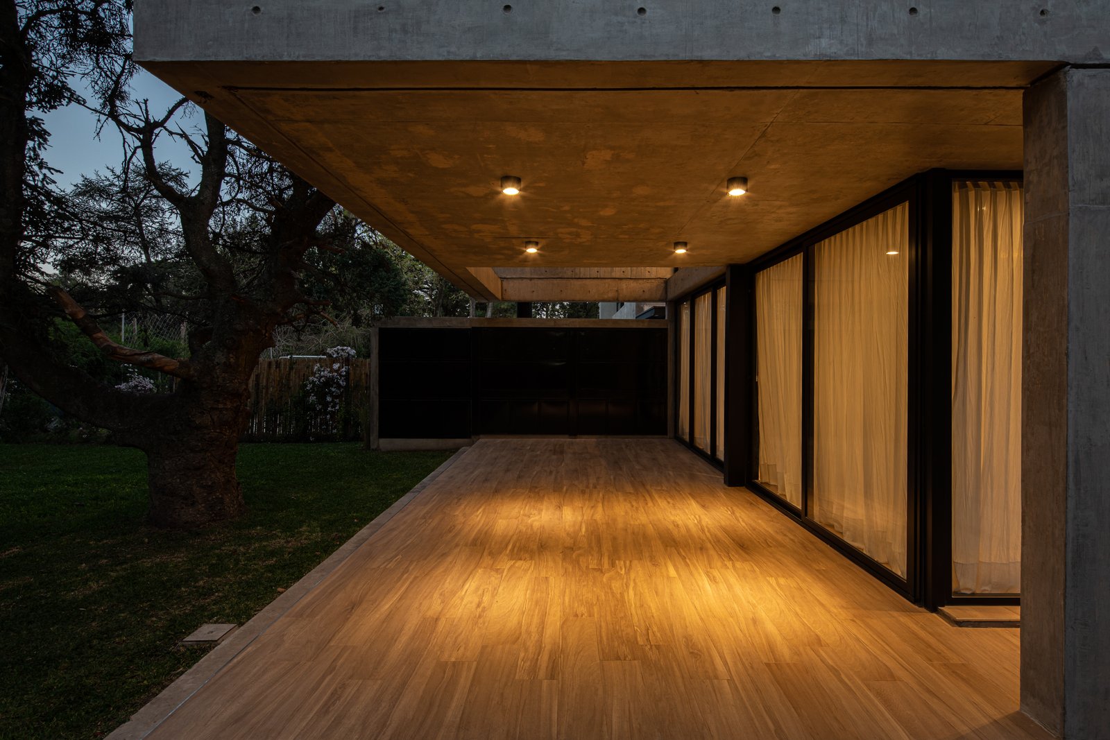 Fachada moderna com deck de madeira e iluminação indireta — projeto Casa Emilia, por Grupo CRBN, em Parque Leloir