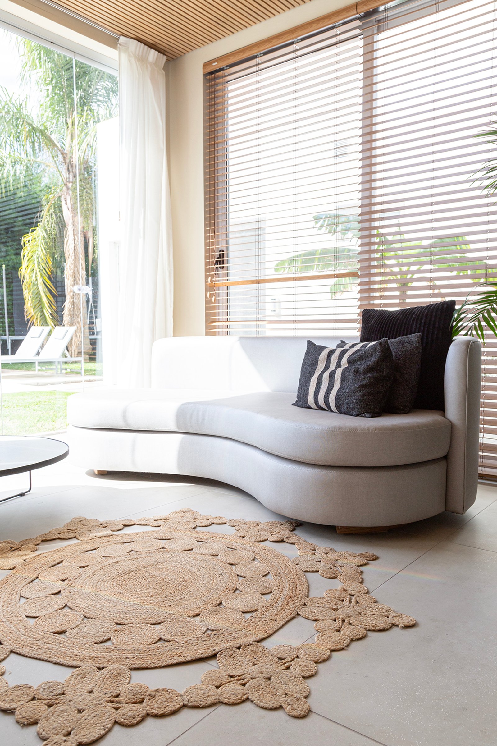 Sala de estar moderna com sofá curvo branco, tapete de juta e teto de madeira — projeto Casa Canning, por Gaby Alfonso, em Canning