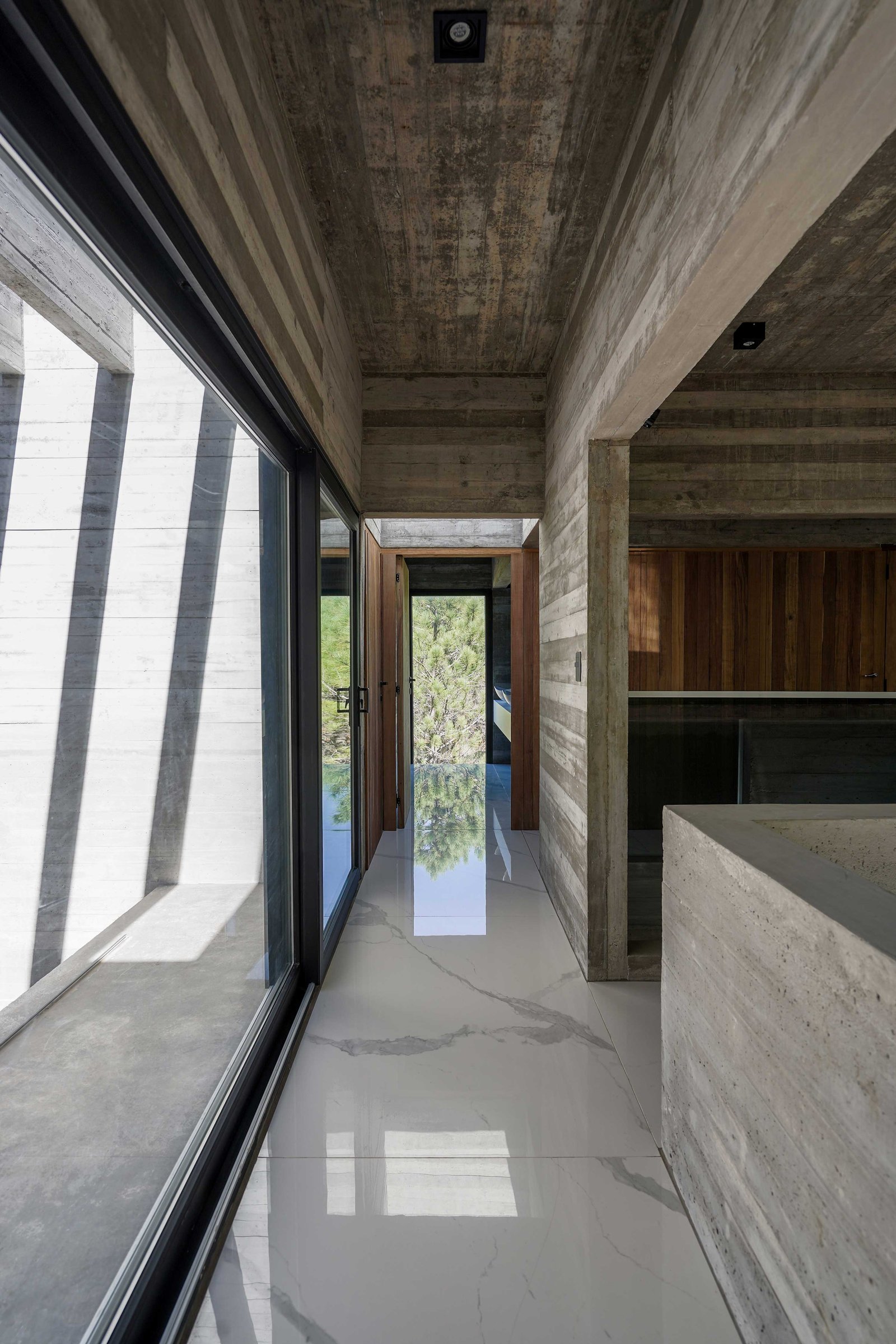 Pasillo minimalista con hormigón visto y suelo de mármol blanco con luz natural — proyecto Casa 4H, por Besonías Almeida arquitectos, en X6VF+67