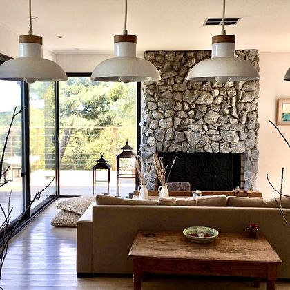 Living moderno con hogar de piedra, ventanales grandes y techo de madera — proyecto Los Medanos Necochea, por Marconi Silva Arquitectos, en Necochea