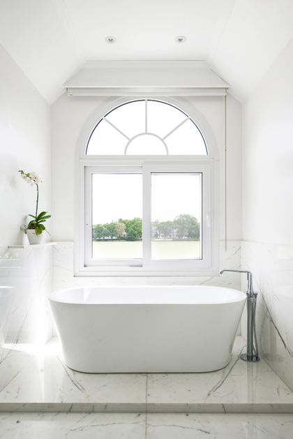 Baño minimalista con bañera blanca frente a ventanal con vista al jardín — proyecto Casa Tortugas , por Estudio Du , en Tortugas Country Club