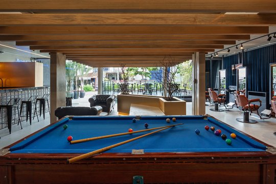 Galería cubierta con mesa de billar azul y vistas al jardín — proyecto SCHAPER BARBEARIA, por Frederico Bicalho Arquitetura