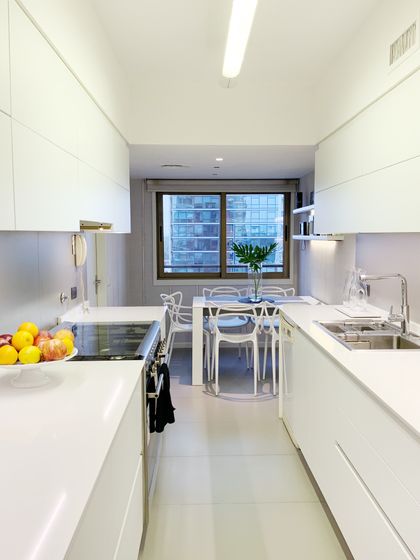 Cocina minimalista blanca con isla, mesada continua y ventanal — proyecto Obra Reforma Cocina Sucre , por @estudioVivianaStaro