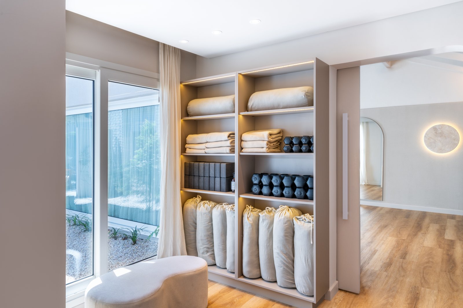 Estantería de estudio de yoga con colchonetas y pesas organizadas — proyecto ALMA MATTER, por Maria Menna Arquitecta, en Mar del Plata