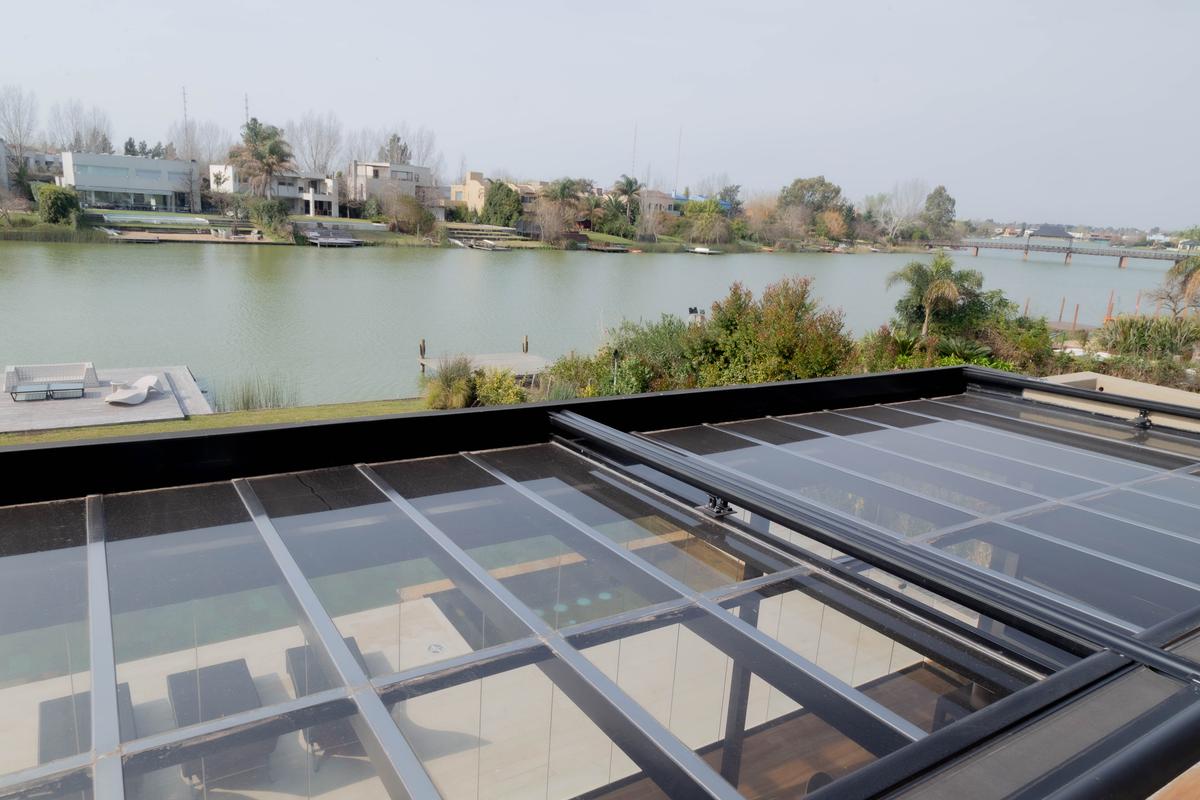 Terraço moderno com teto de vidro retrátil e vista para o lago — projeto TOLDER - TOLDOS, por Argentina en Obra 2024, em Rincón de Milberg