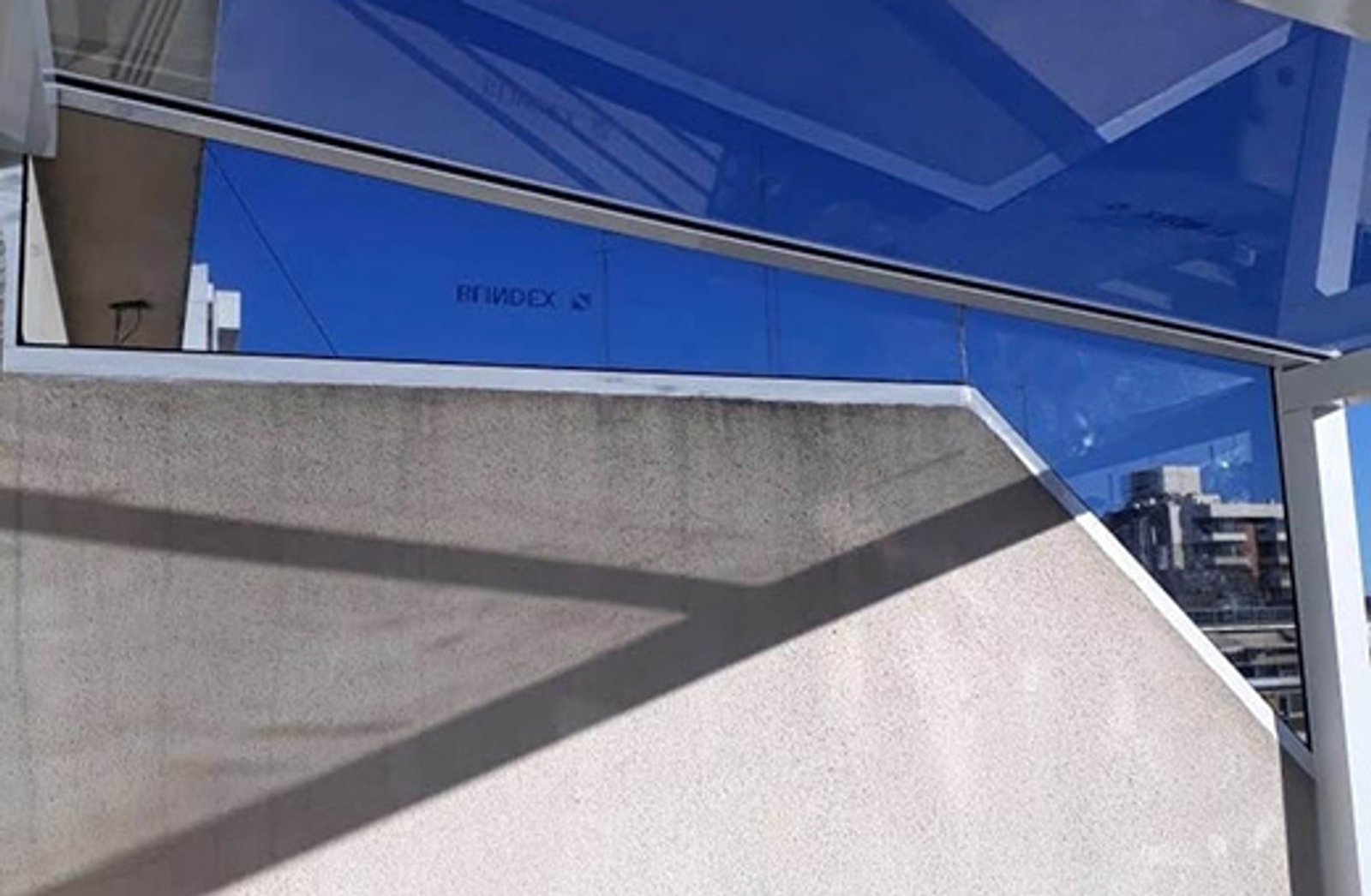 Fachada moderna con muro de hormigón y vidrio reflectante — proyecto Techos en vidrio laminado, por Cristalcenter, en Parque Leloir