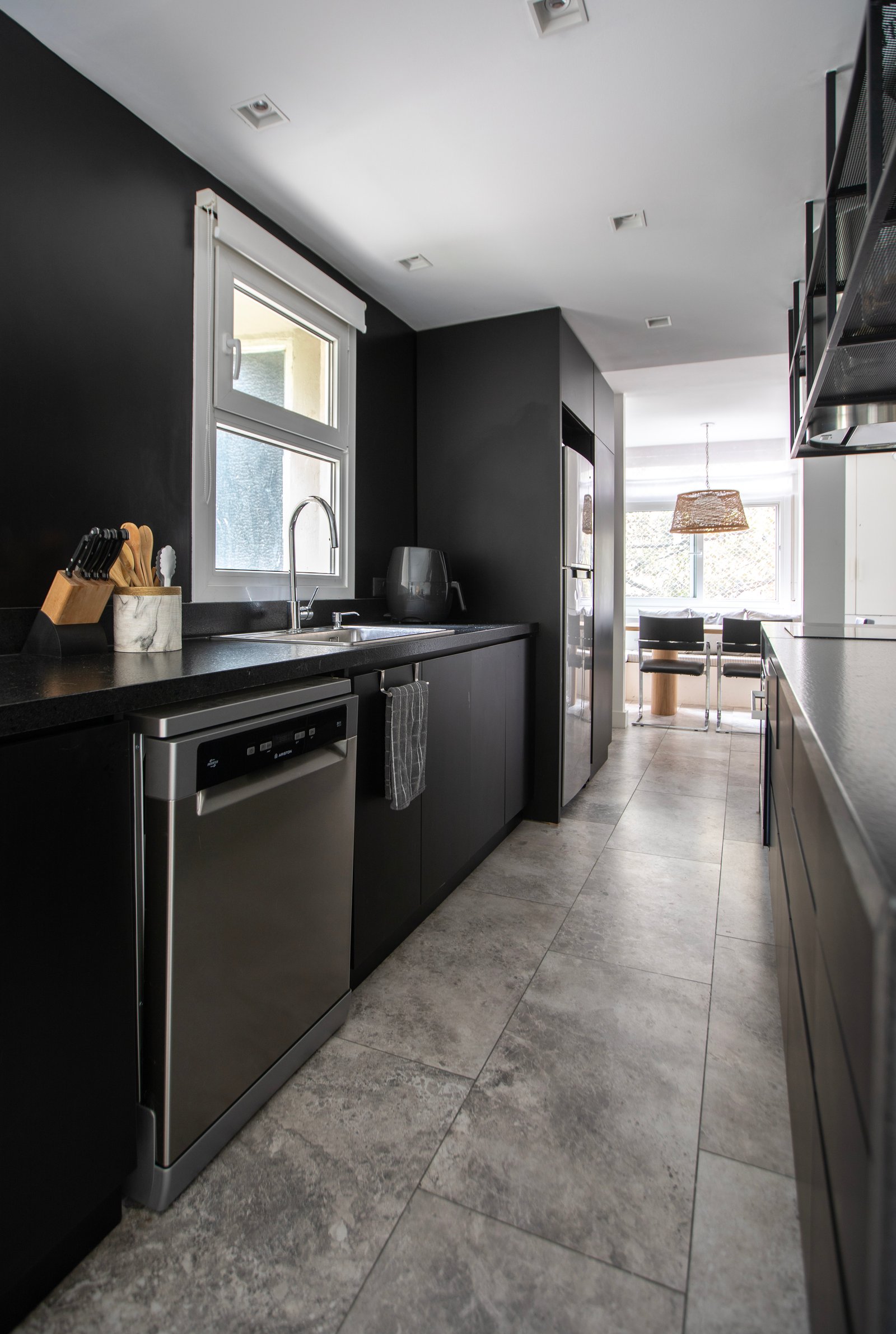 Cocina moderna minimalista con gabinetes negros y piso de piedra gris — proyecto PROYECTO PARQ, por ILVA, en Provincia de Buenos Aires