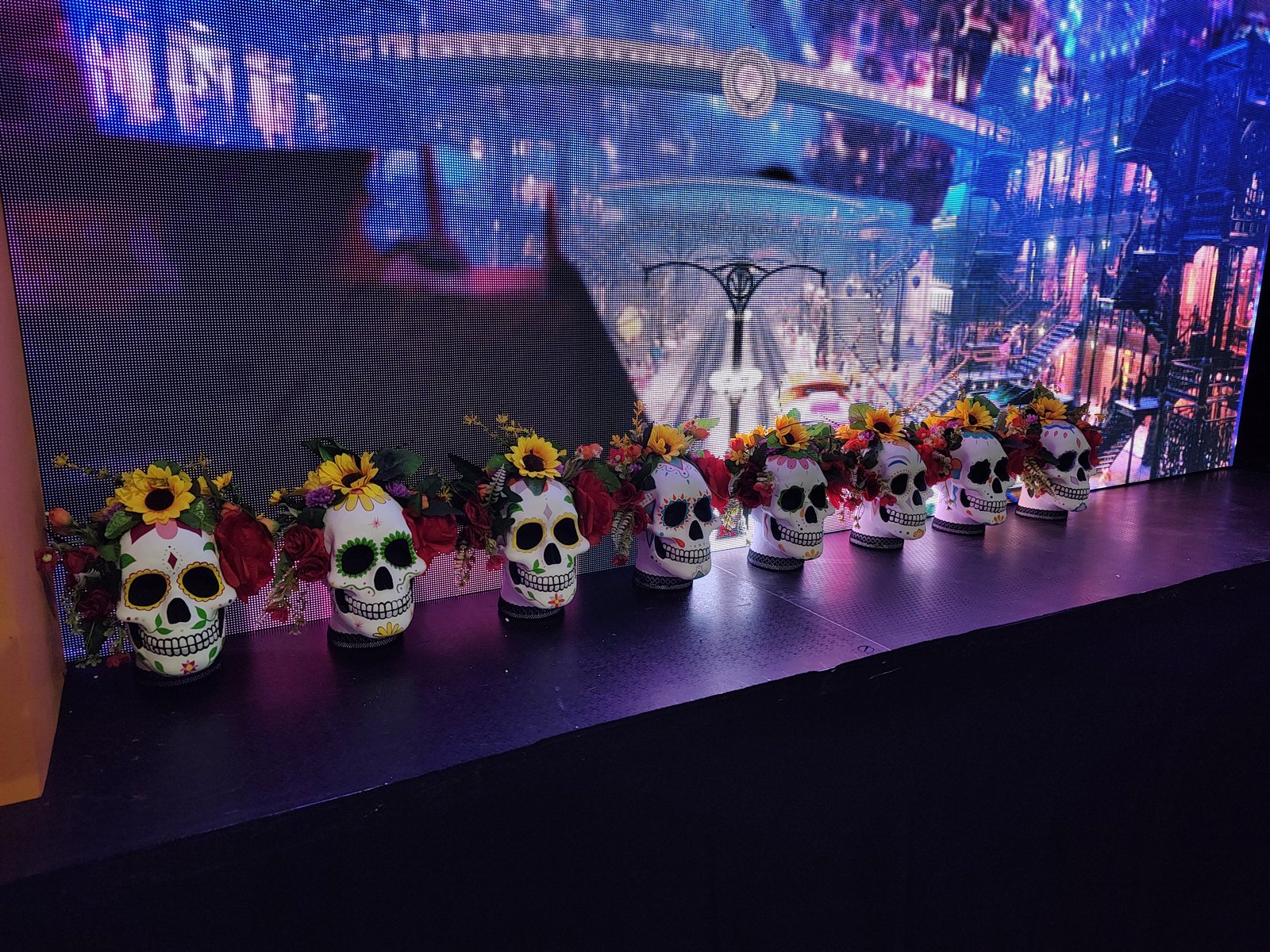 calaveras decorativas con flores frente a pantalla luminosa — proyecto Calaveras y Catrinas, por Arte Umbra, en Cdad. Autónoma de Buenos Aires