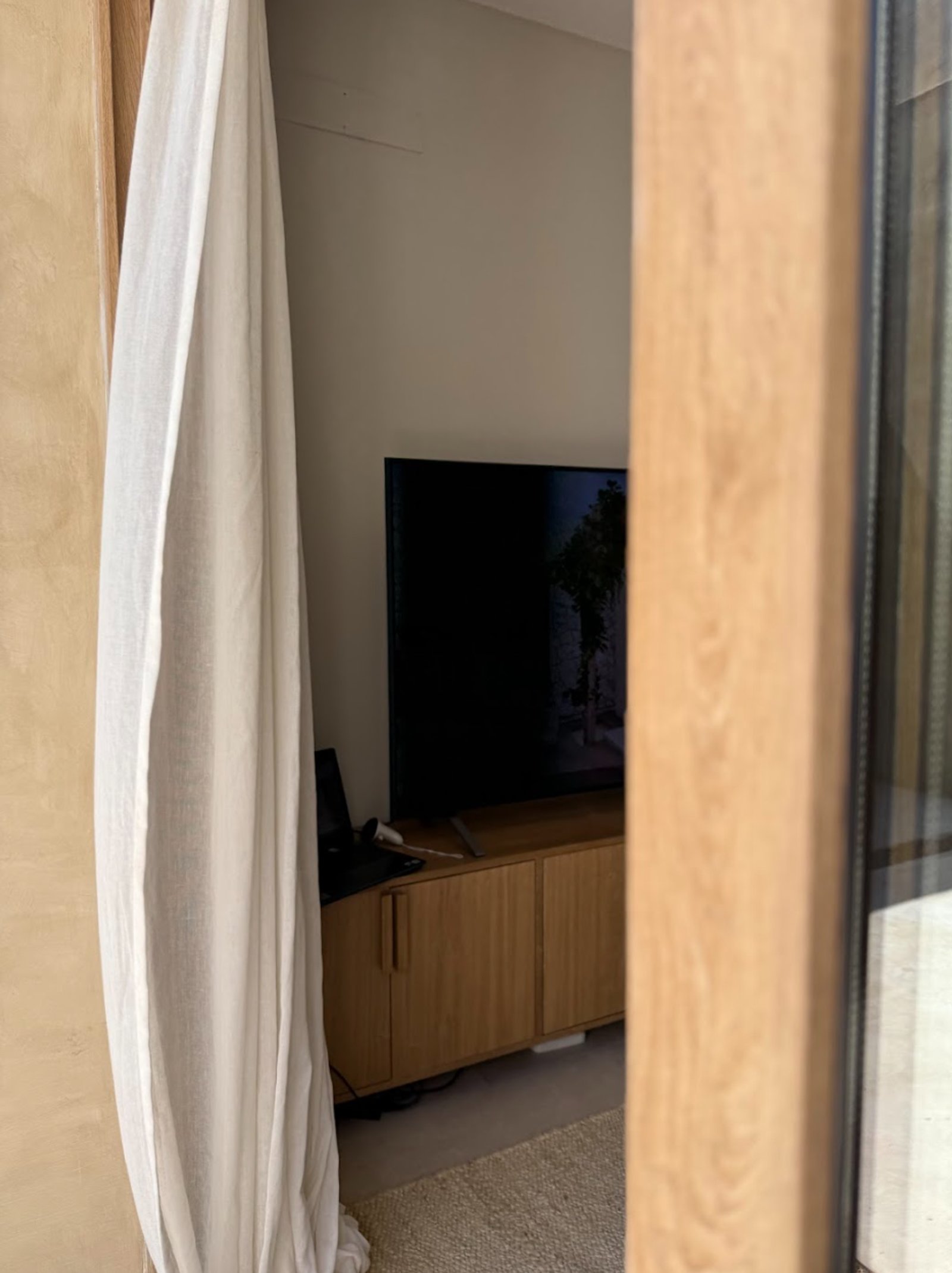 Sala de estar moderna com móvel baixo de madeira e cortinas brancas — projeto La Verbena, por Grupo Pauta Arquitectura, em Alejandro Korn 3150