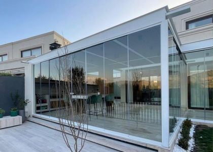 Galería vidriada moderna con piso de hormigón y vista al jardín — proyecto BARRIO CARPINCHOS, NORDELTA, por CERRAMIENTOS PANORAMICOS, en Benavidez