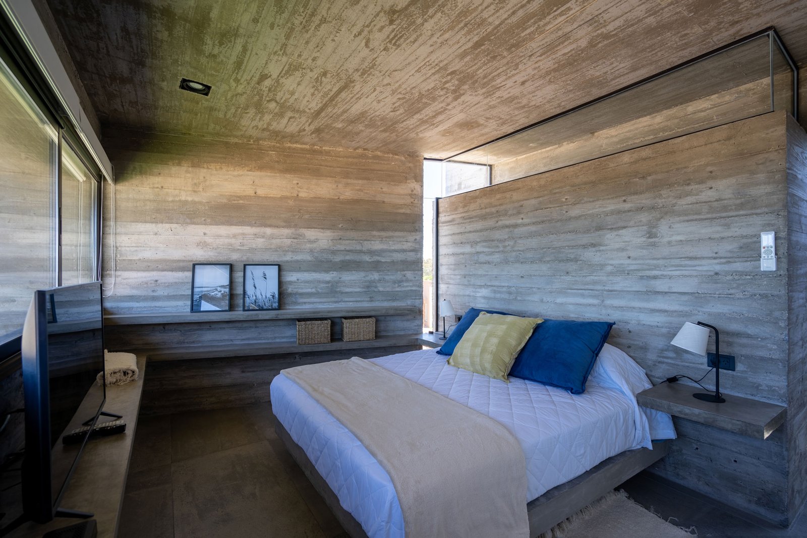 Dormitorio minimalista de hormigón visto con amplios ventanales — proyecto Casa La Marina, por Besonías Almeida arquitectos, en X6VF+67