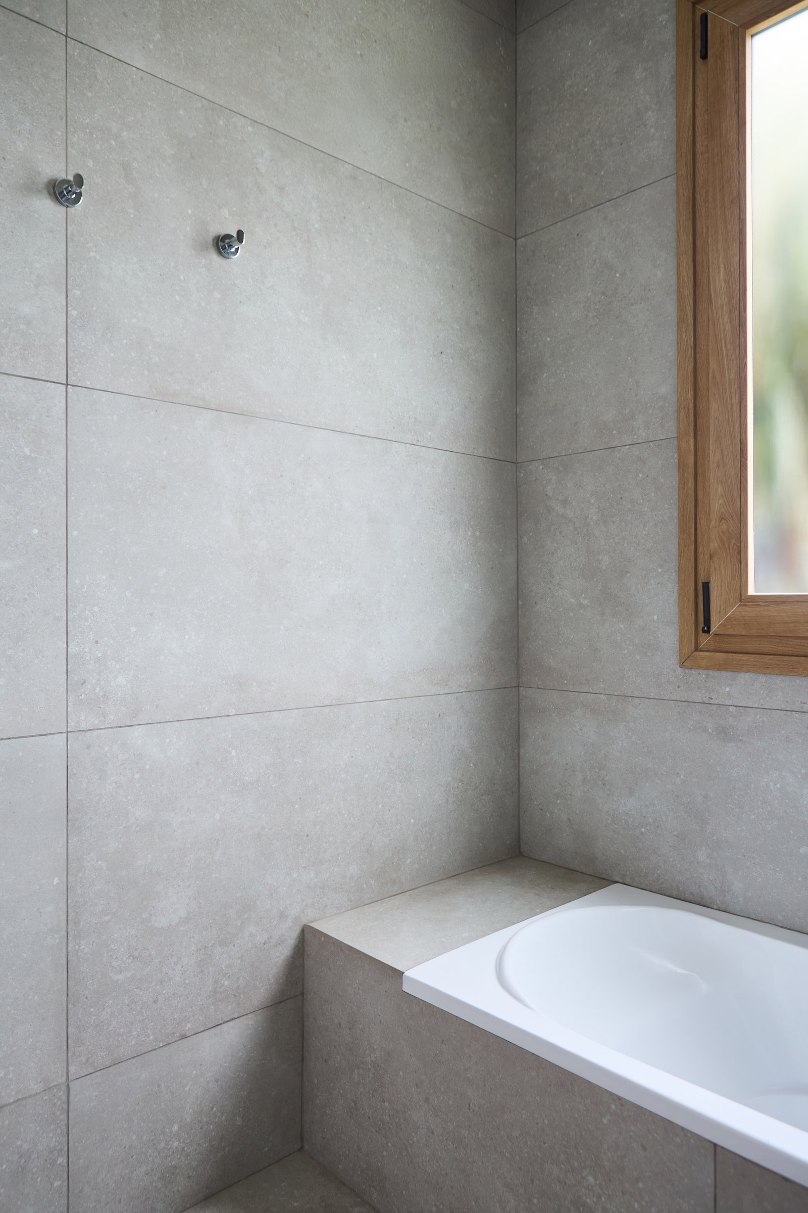 Banheiro moderno com banheira freestanding e revestimento cerâmico cinza — projeto Baños, por CASA1-TROMEN, em Bella Vista