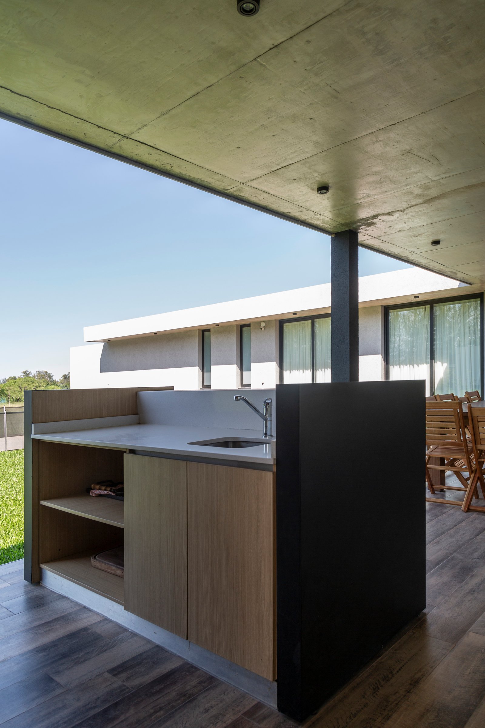 Cocina exterior moderna con techo de hormigón y muebles de madera — proyecto Casa Cruz , por Grupo CRBN, en B2812 Exaltación de la Cruz