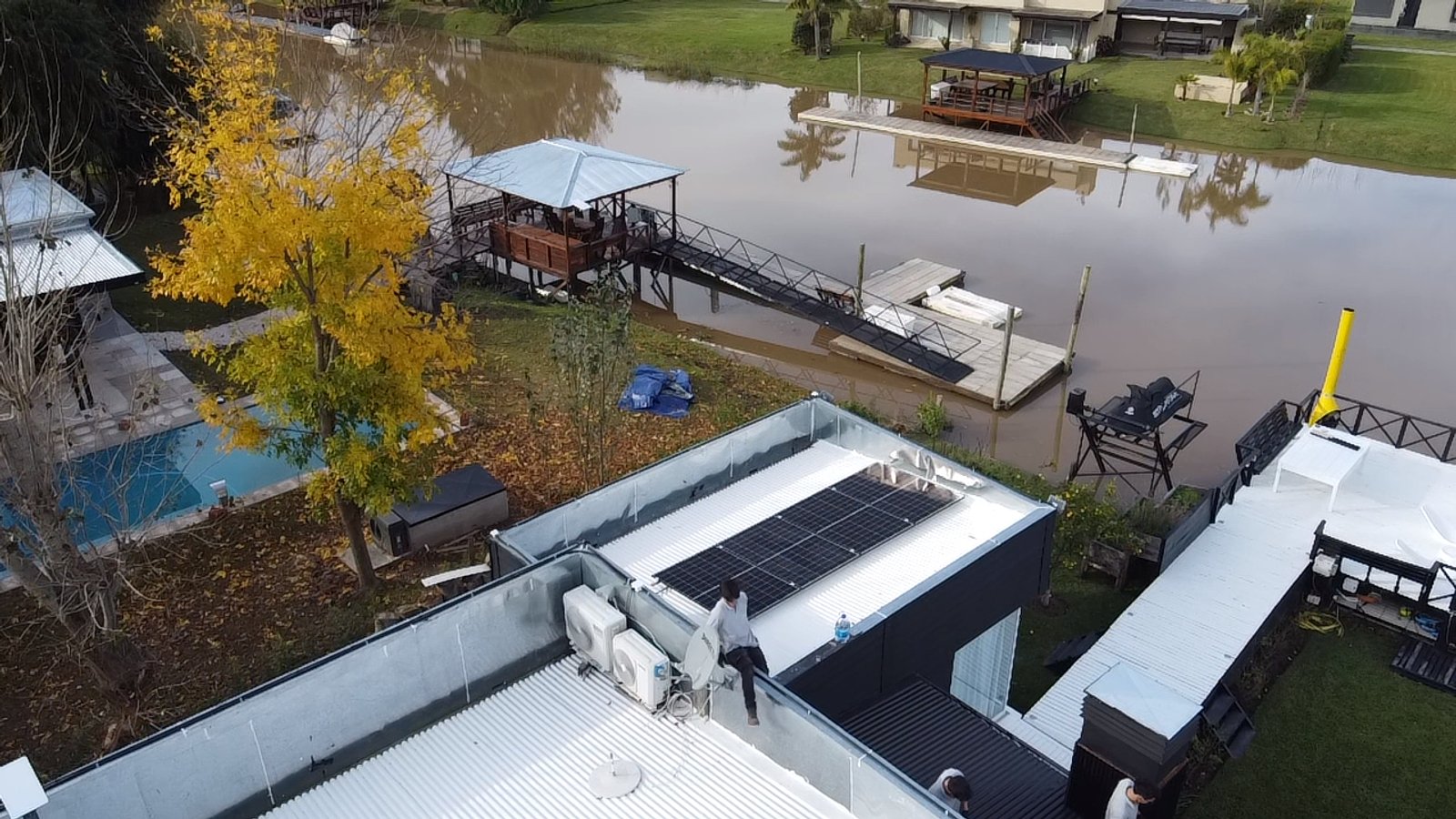 Fachada moderna sobre canal con piscina y deck — proyecto Isla del Este, por efergía, en Delta