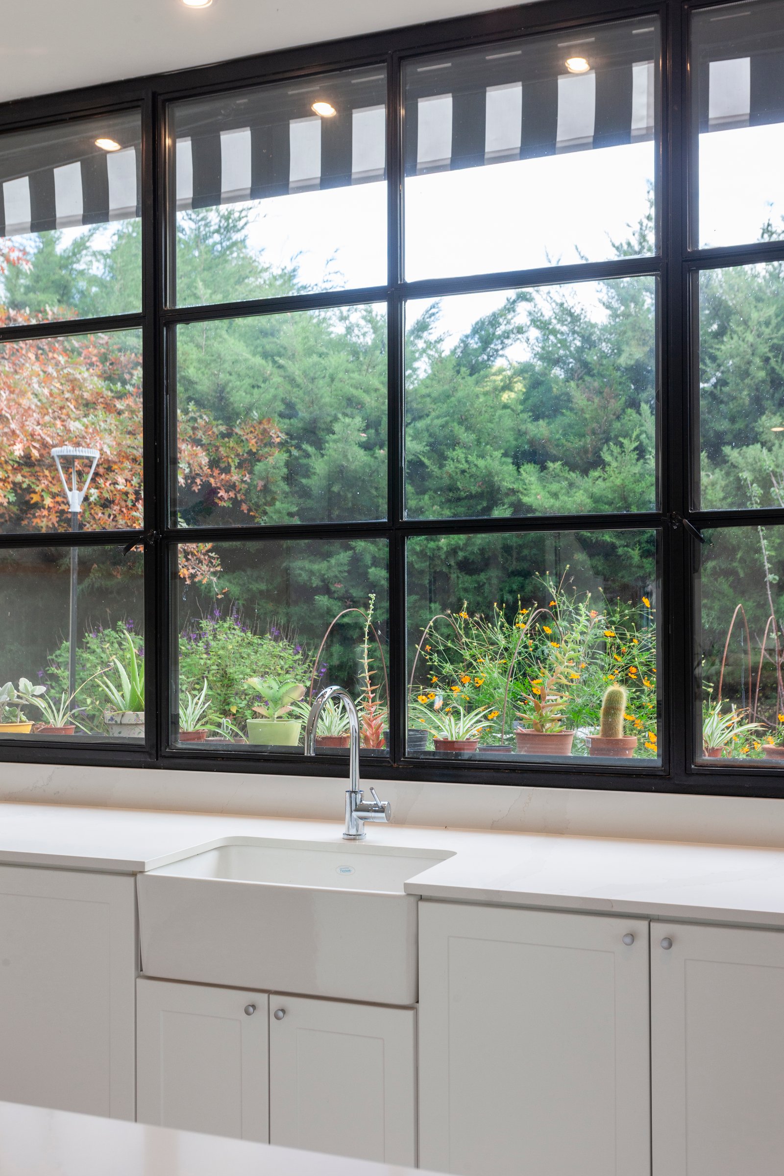 Cocina moderna con vista al jardín, ventanas amplias y lavabo blanco — proyecto CASA HS143, por A'PRIMA - Arquitectura Sustentable, en km 7.5 Ruta 25