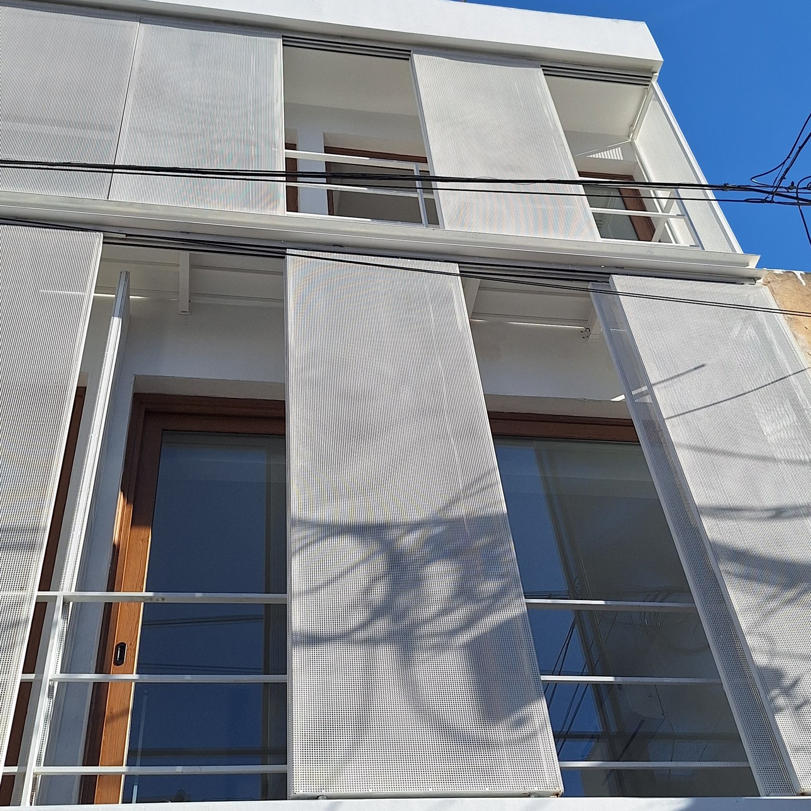 fachada moderna con pantallas metálicas perforadas y ventanas amplias — proyecto Edificio Escribano, por LW Lopez Wolder arquitectos, en Pasaje Escribano 66