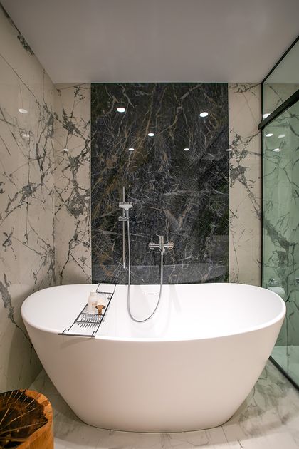 Bano minimalista con banera redonda blanca y revestimiento marmol negro — proyecto Casa Oroño, por Estudio Plats, en Buenos Aires