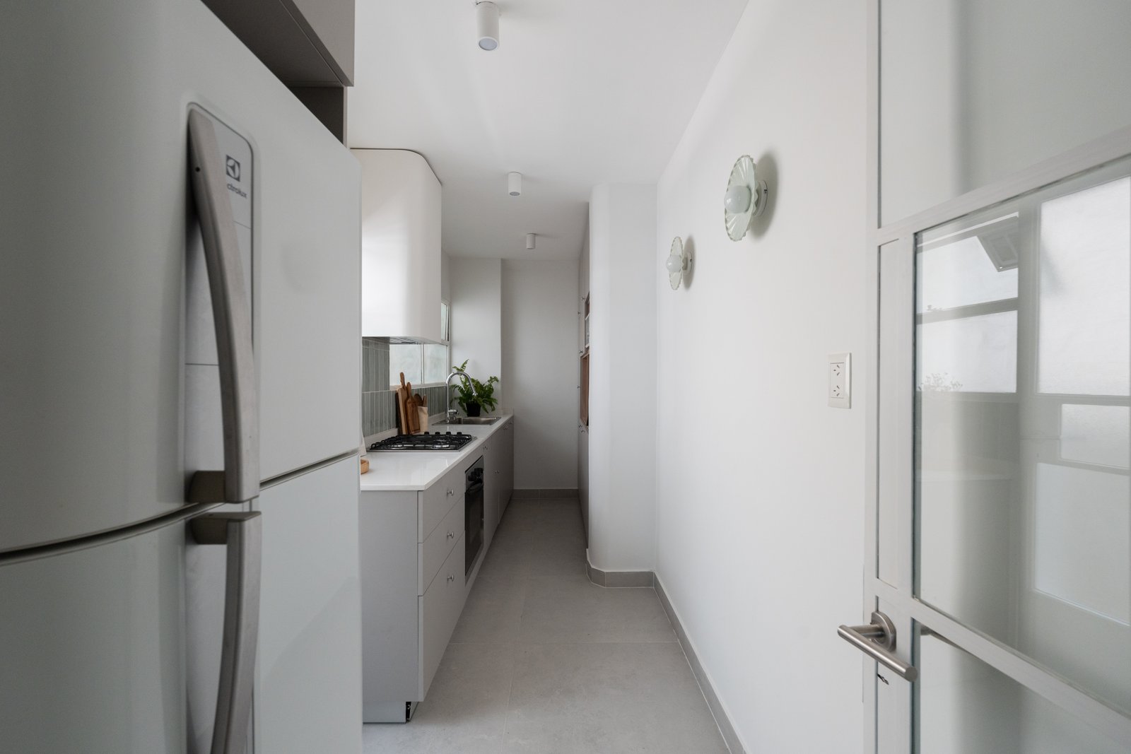 Cozinha moderna em corredor com geladeira branca grande e acabamentos cinza — projeto Guemes, por Estudio BDM, em Palermo
