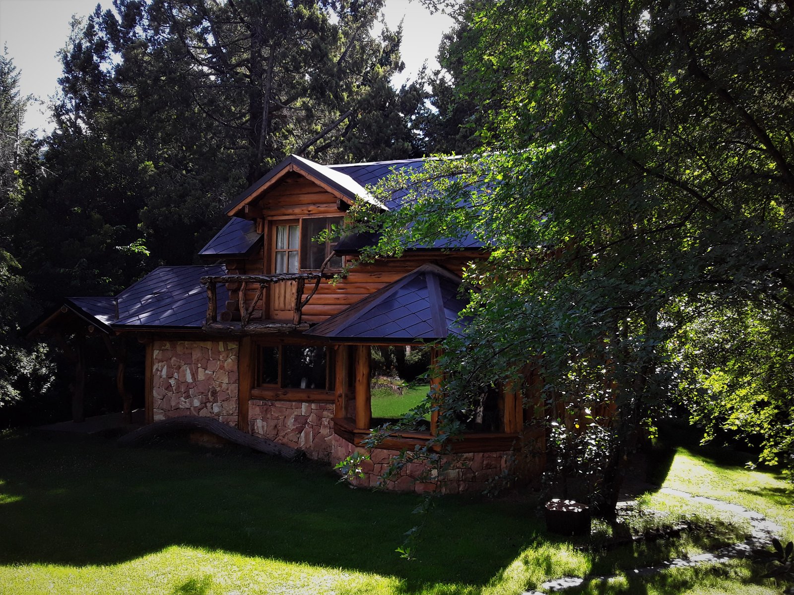 Casa rústica de madeira e pedra em floresta exuberante — projeto Casa Familiar VILLA ARELAUQUEN - SAN CARLOS DE BARILOCHE, por arquiga10573853, em San Carlos de Bariloche