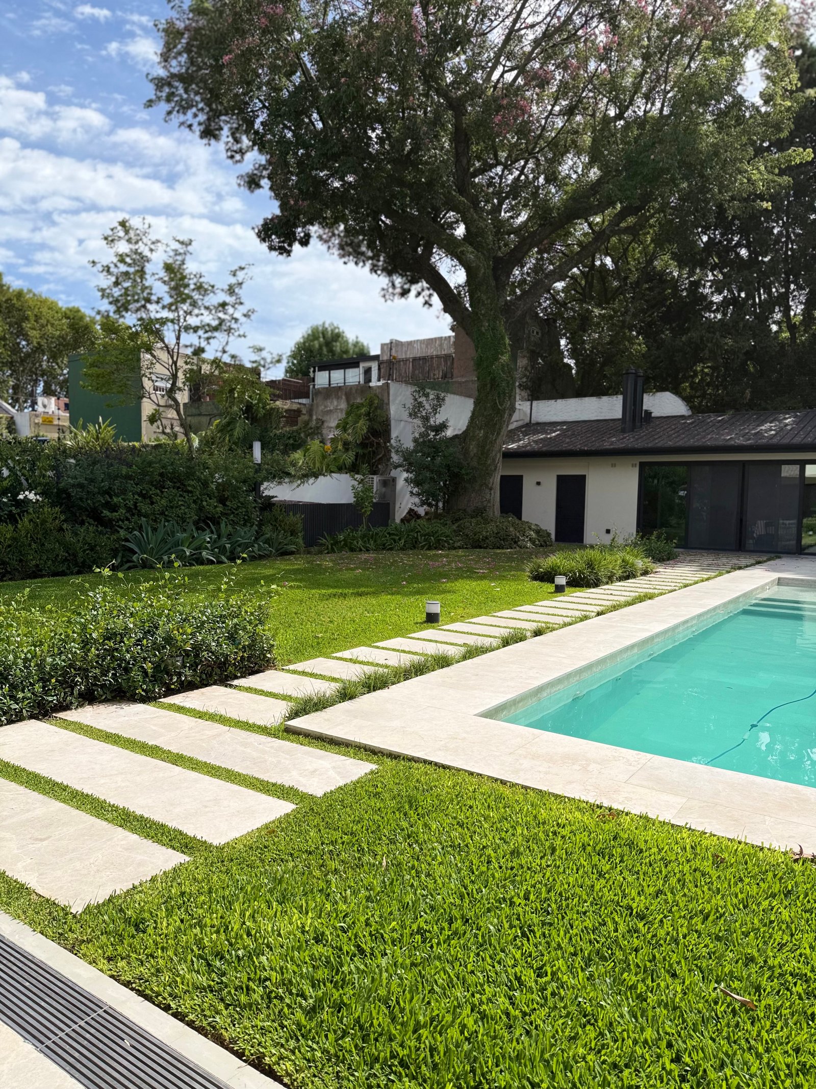Área de piscina moderna com caminho de pedra e gramado exuberante — projeto VICENTE LOPEZ, por Baires Green, em Vicente López