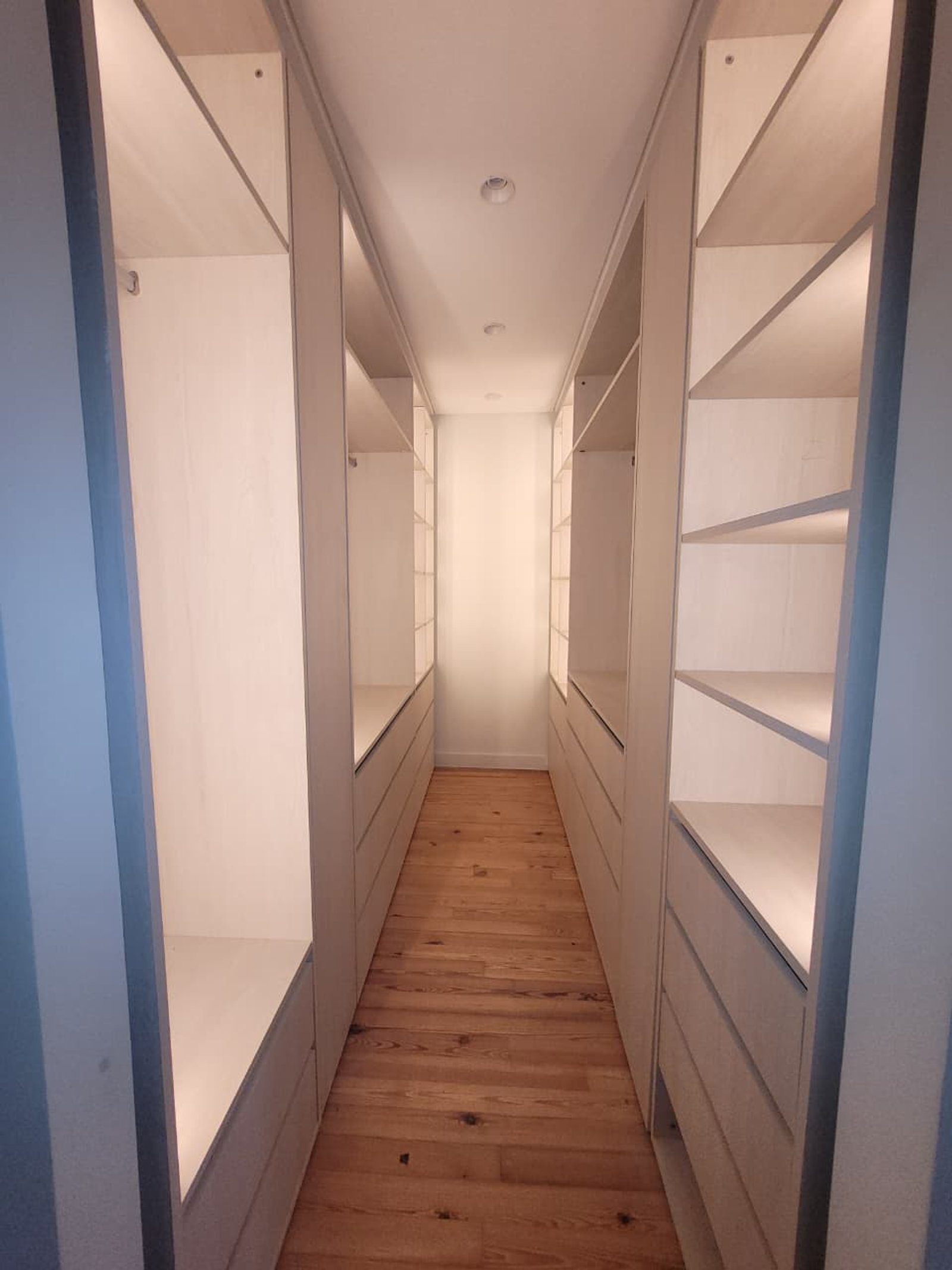 Corredor de closet moderno com armários brancos e iluminação indireta — projeto Belgrano, por Licefe Carpentry SRL, em Belgrano