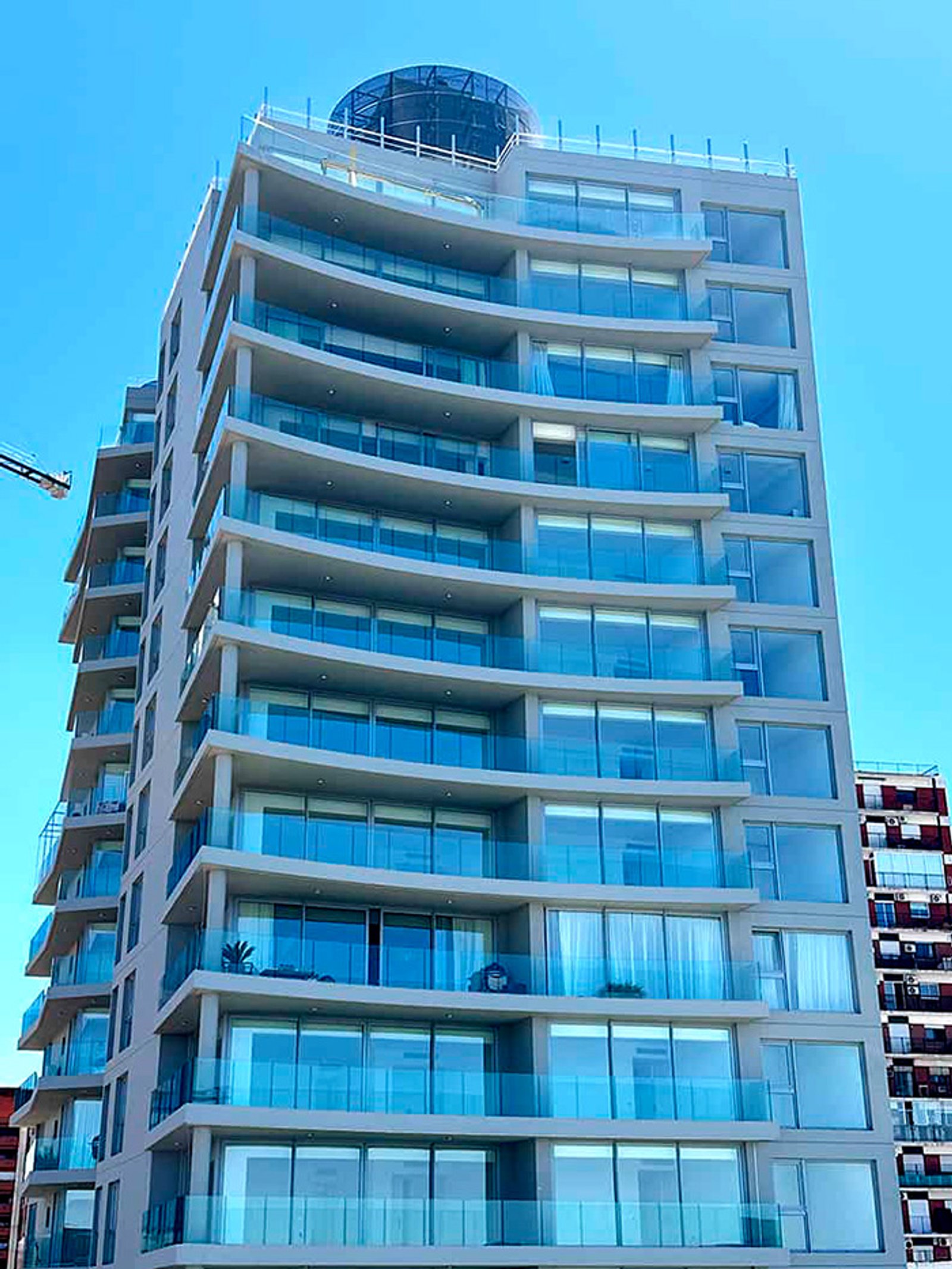 Edificio moderno con balcones curvos de vidrio y fachada vidriada — proyecto Libertador Blvd, por MUCHTEK, en Vicente López