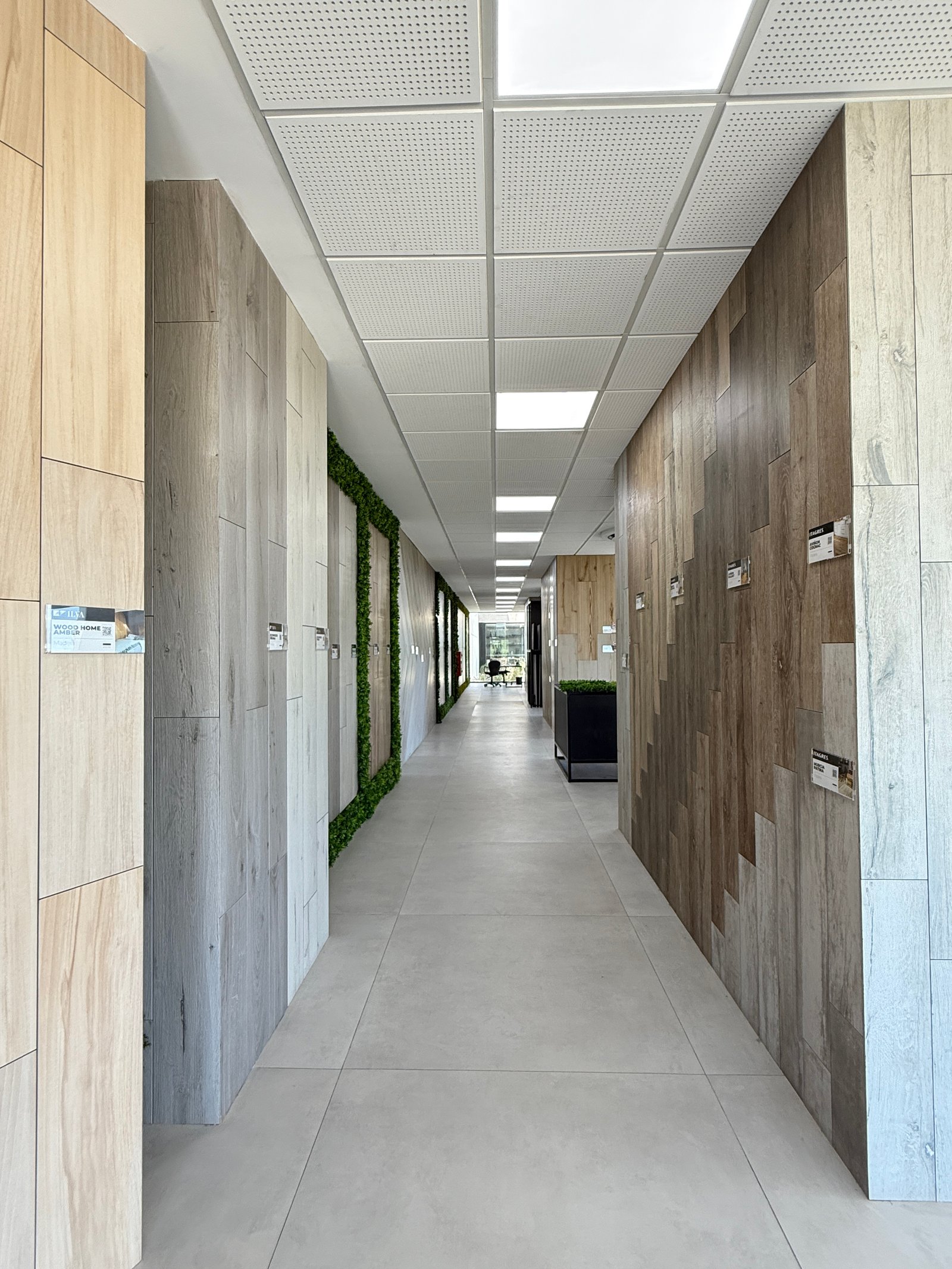 Corredor moderno com painéis de madeira e pedra e iluminação indireta — projeto Showroom, por GAP HAUS, em Calle Austria Nte. 2450