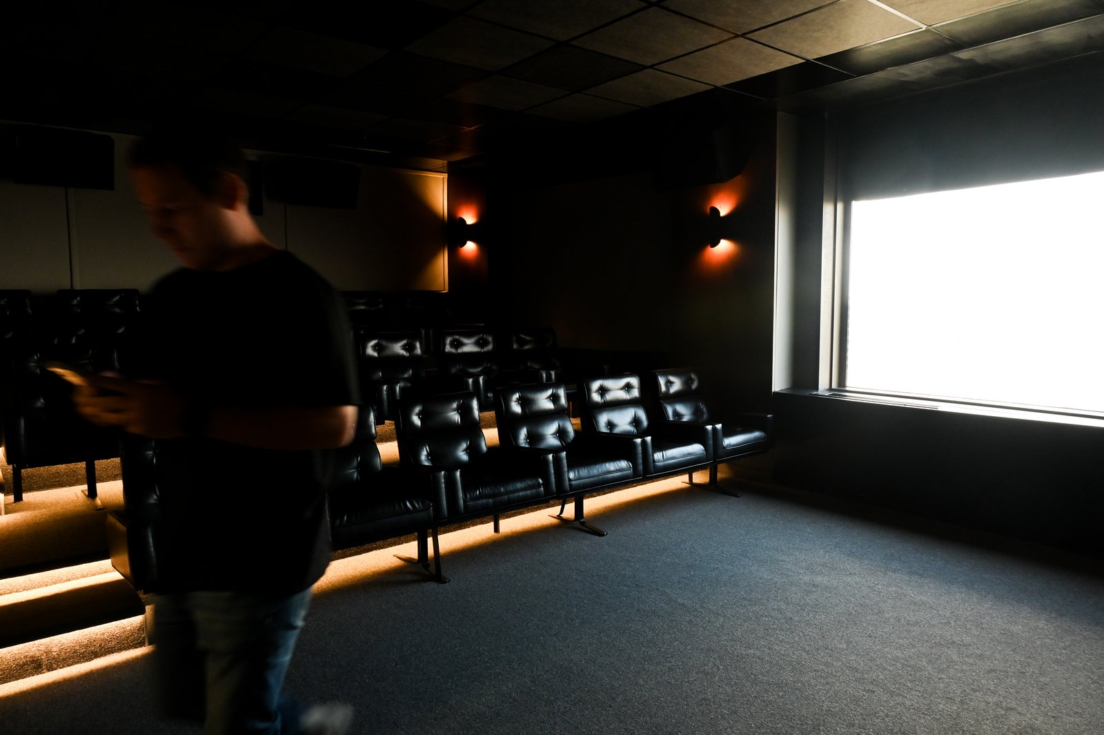 interior de sala de cinema escura com assentos — projeto Oficinas UIP, por cromo., em Retiro