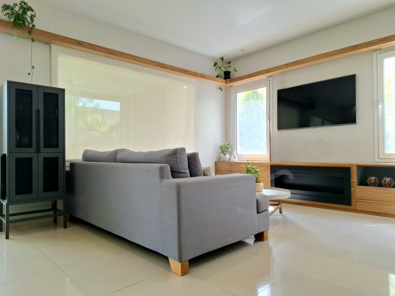 Living moderno con sofá gris y detalles en madera — proyecto PROYECTO TIPAS, por HALESA ESTUDIO, en Las Tipas
