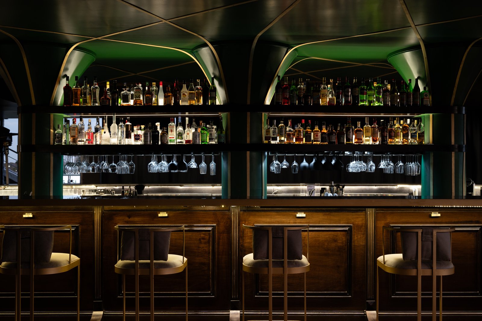 Bar de lujo con estanterías de madera oscura y luces cálidas — proyecto PRESIDENTE BAR HIPODROMO, por AB ARQUITECTURA, en San Isidro