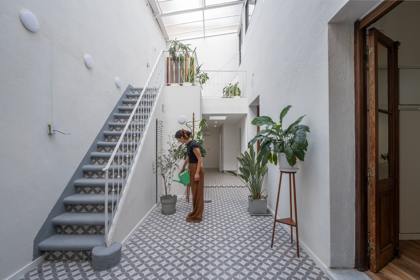 Corredor moderno com escada flutuante e átrio aberto — projeto Casa Patio, por Herrera Ungaro, em San Cristóbal