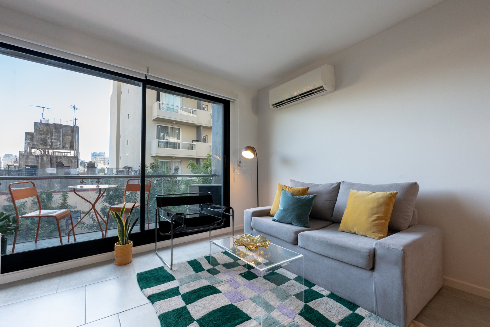 Living moderno con balcón y vista urbana — proyecto Rawson, por Estudio BDM, en Almagro