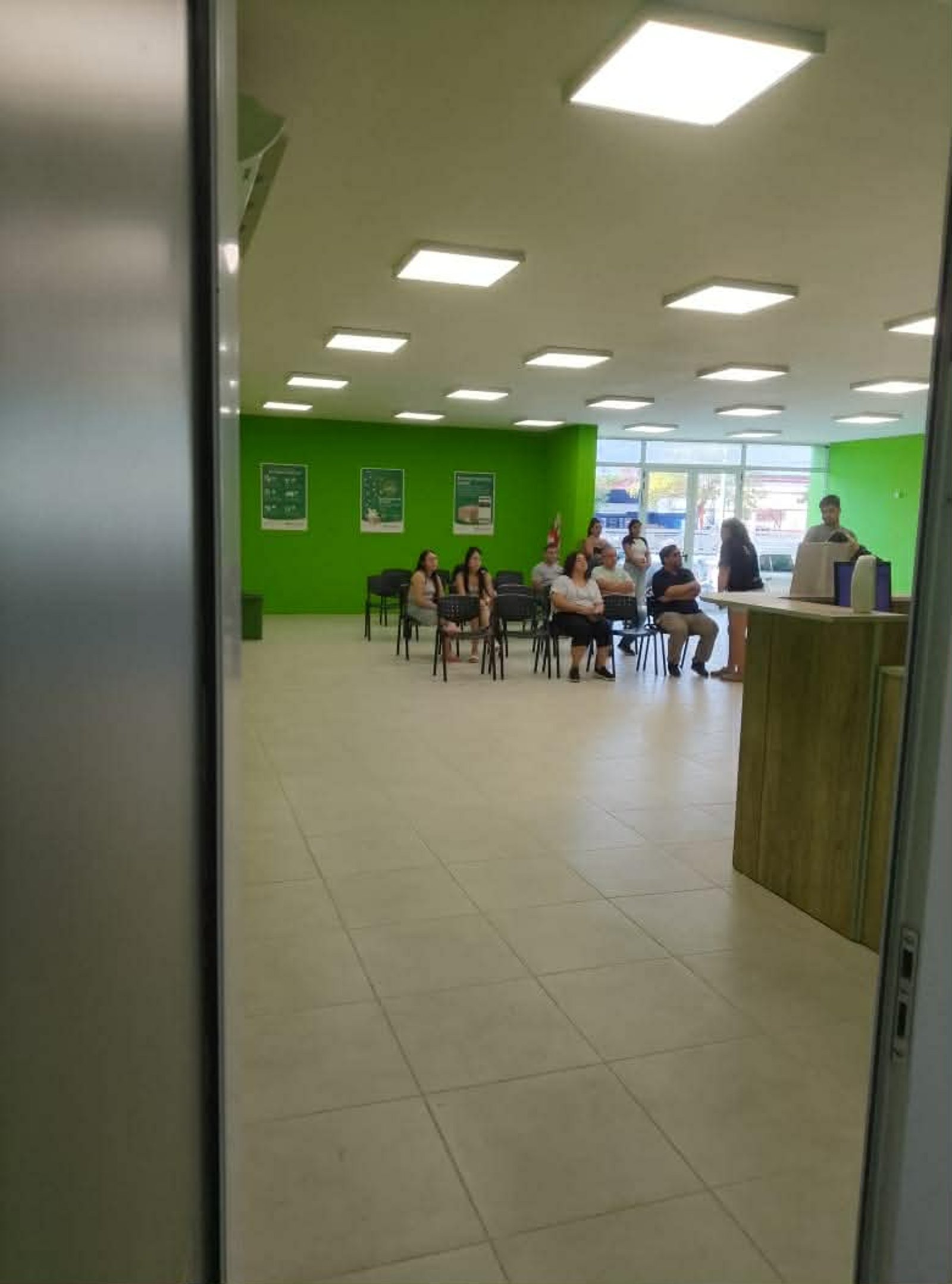 Sala de espera comercial con paredes verdes brillantes y suelo de baldosas — proyecto Sucursal Via Cargo, filial Corrientes, Empresa de distribución y logística., por Arquitecto Gu