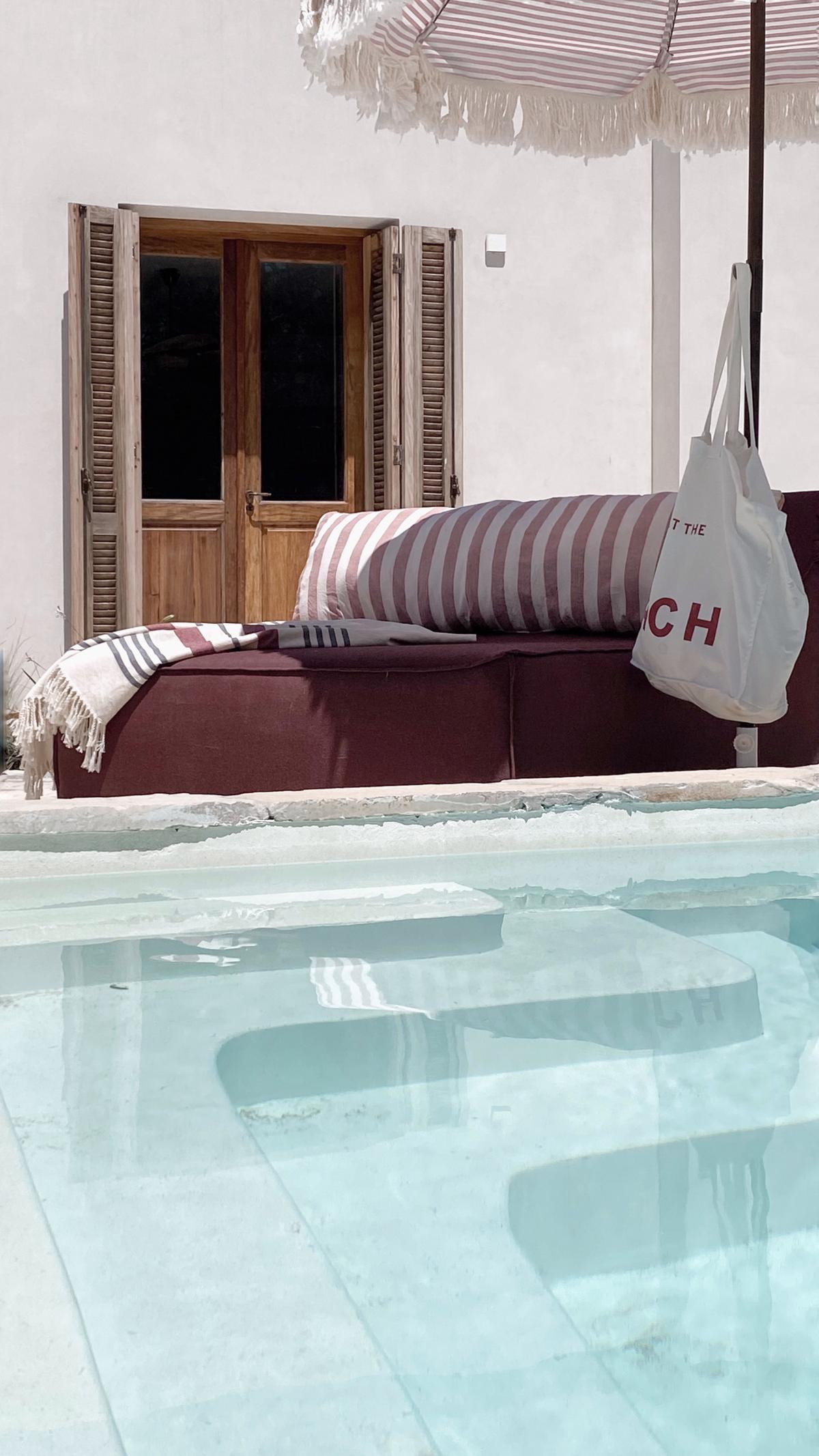 Área de piscina com lounge e detalhes listrados — projeto El Refugio, por Grupo Pauta Arquitectura, em Pinamar