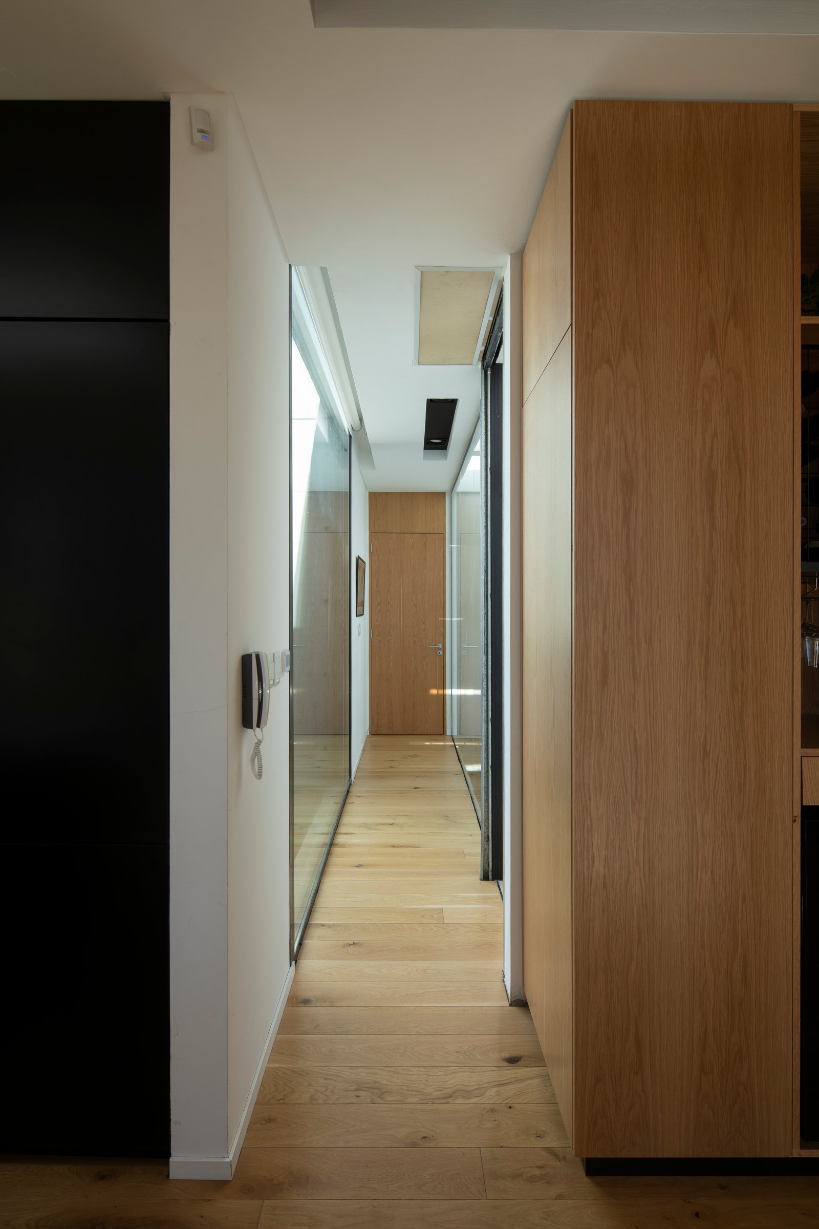 Pasillo moderno con pisos de madera y paneles de roble — proyecto Casa MECHA, por Grupo CRBN, en B1712 Castelar