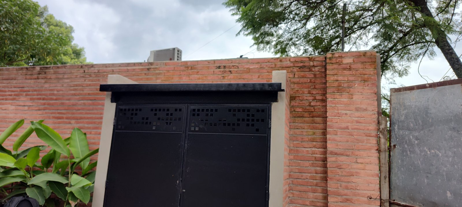 fachada de tijolos com portão preto — projeto GARDEN OFFICE, por HMCONSTRUCCIONES, em San Lorenzo 146
