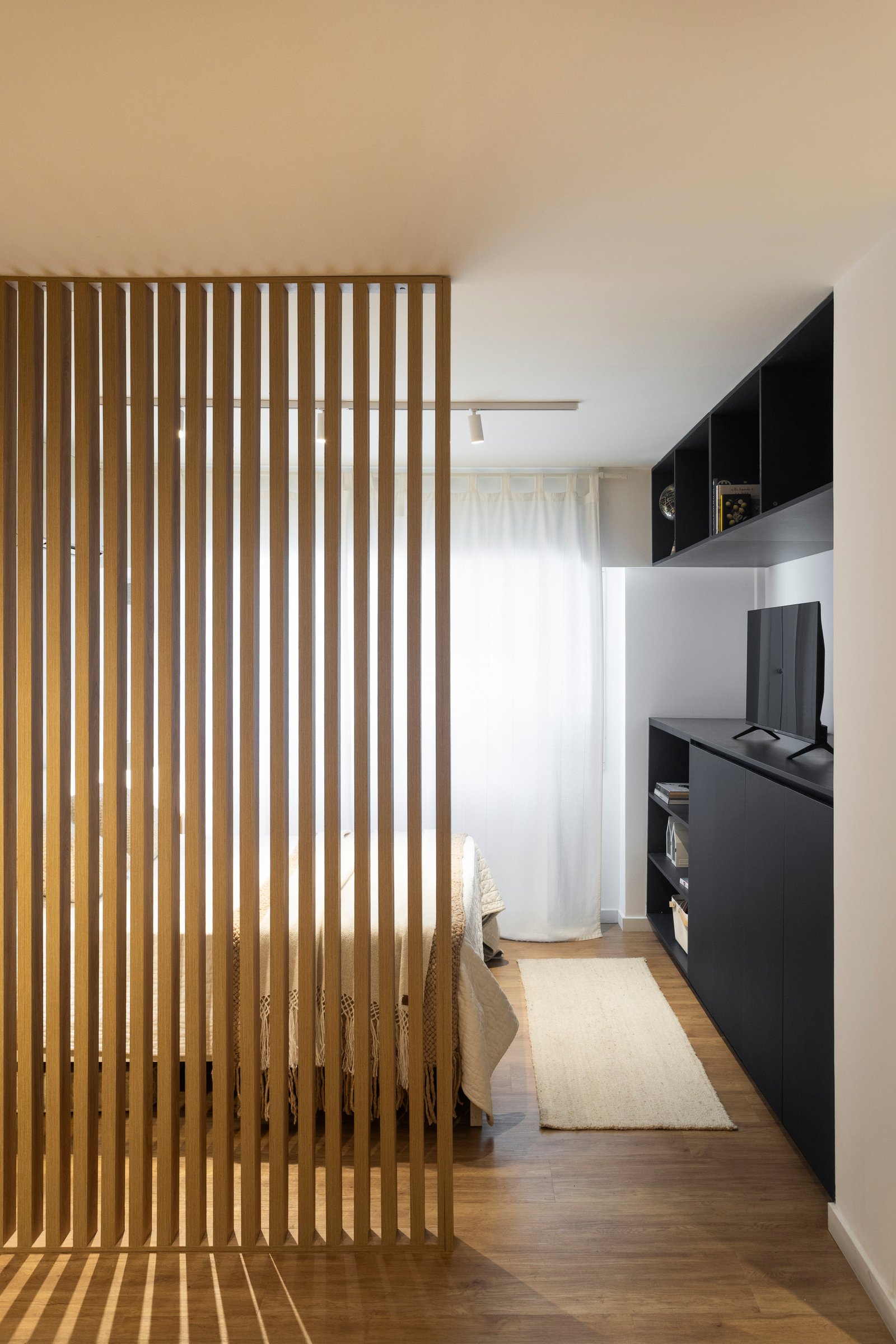 Divisória de ripas de madeira e estante preta em quarto moderno — projeto REFORMA NE, por Rastro Estudio, em Palermo