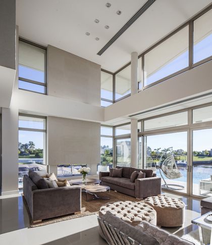 Living moderno de doble altura con grandes ventanales y chimenea — proyecto Casa Caledoiscopio, por Apaarquitectura, en Nordelta