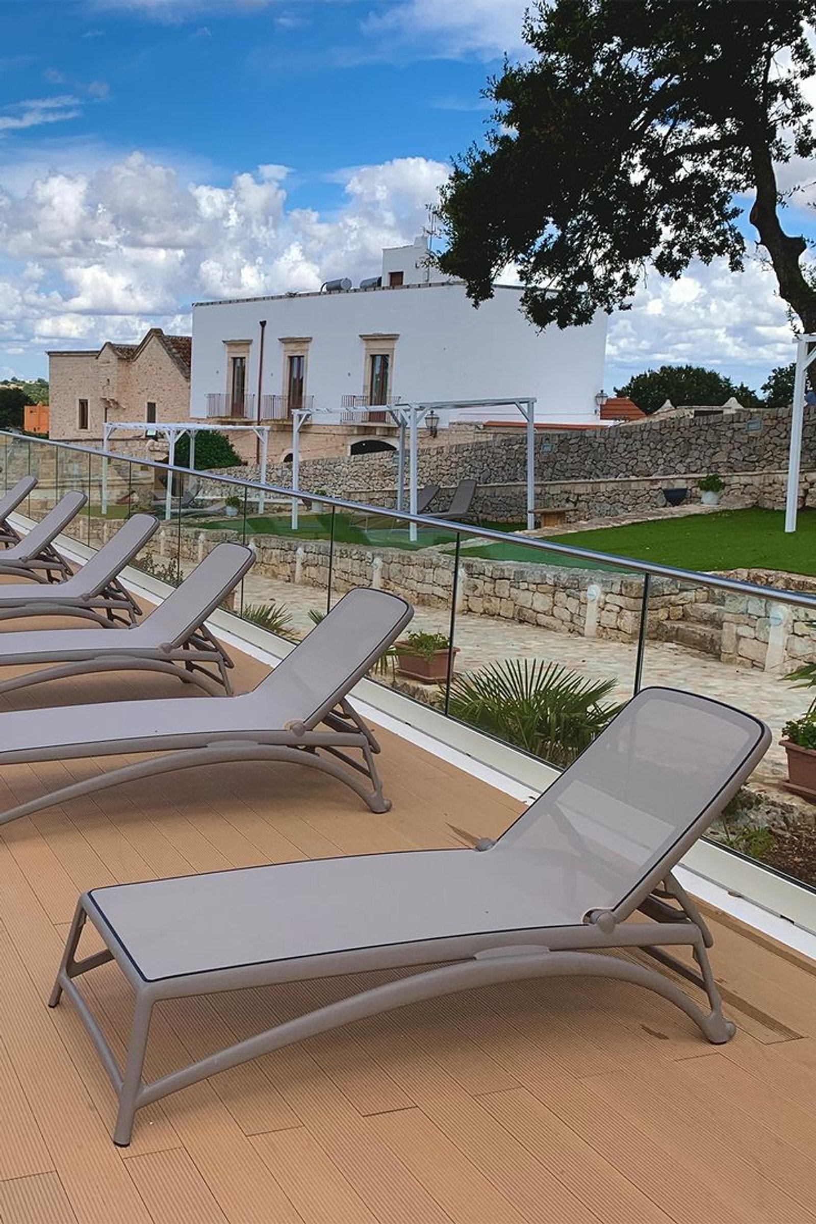 terraza moderna con tumbonas grises y villa mediterránea — proyecto Reposeras NARDI®, por Casa Nuñez