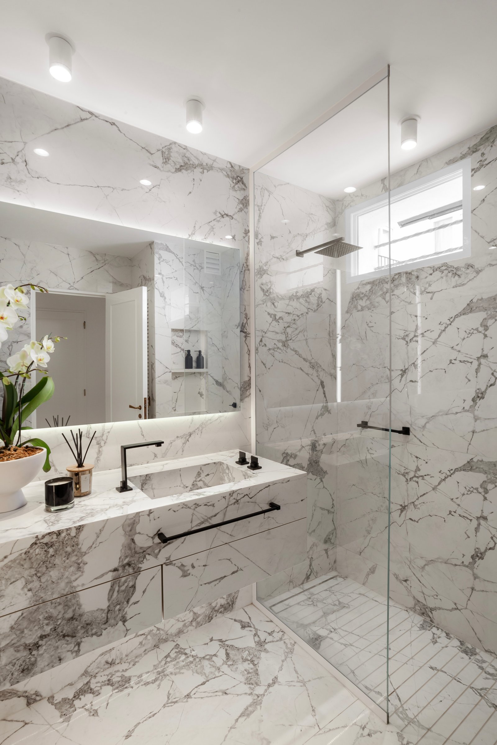 baño moderno con revestimiento de mármol, grifería negra y ducha de cristal — proyecto Alvear | Redefining luxury, por Ren Studio, en Recoleta