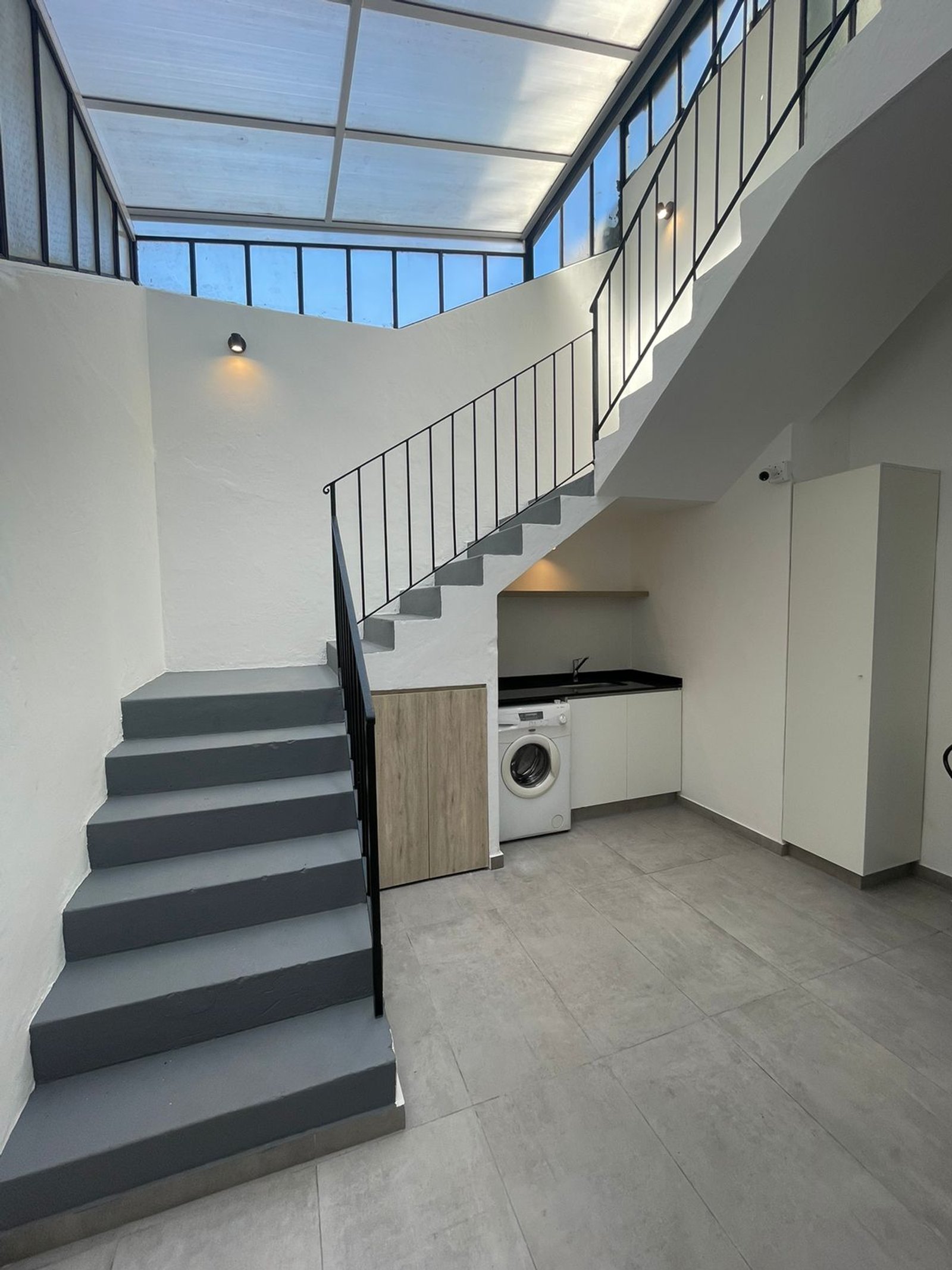 Escalera flotante moderna con tragaluz y lavadora — proyecto Carranza , por Estudio NET Arquitectura , en Adolfo P. Carranza 2263