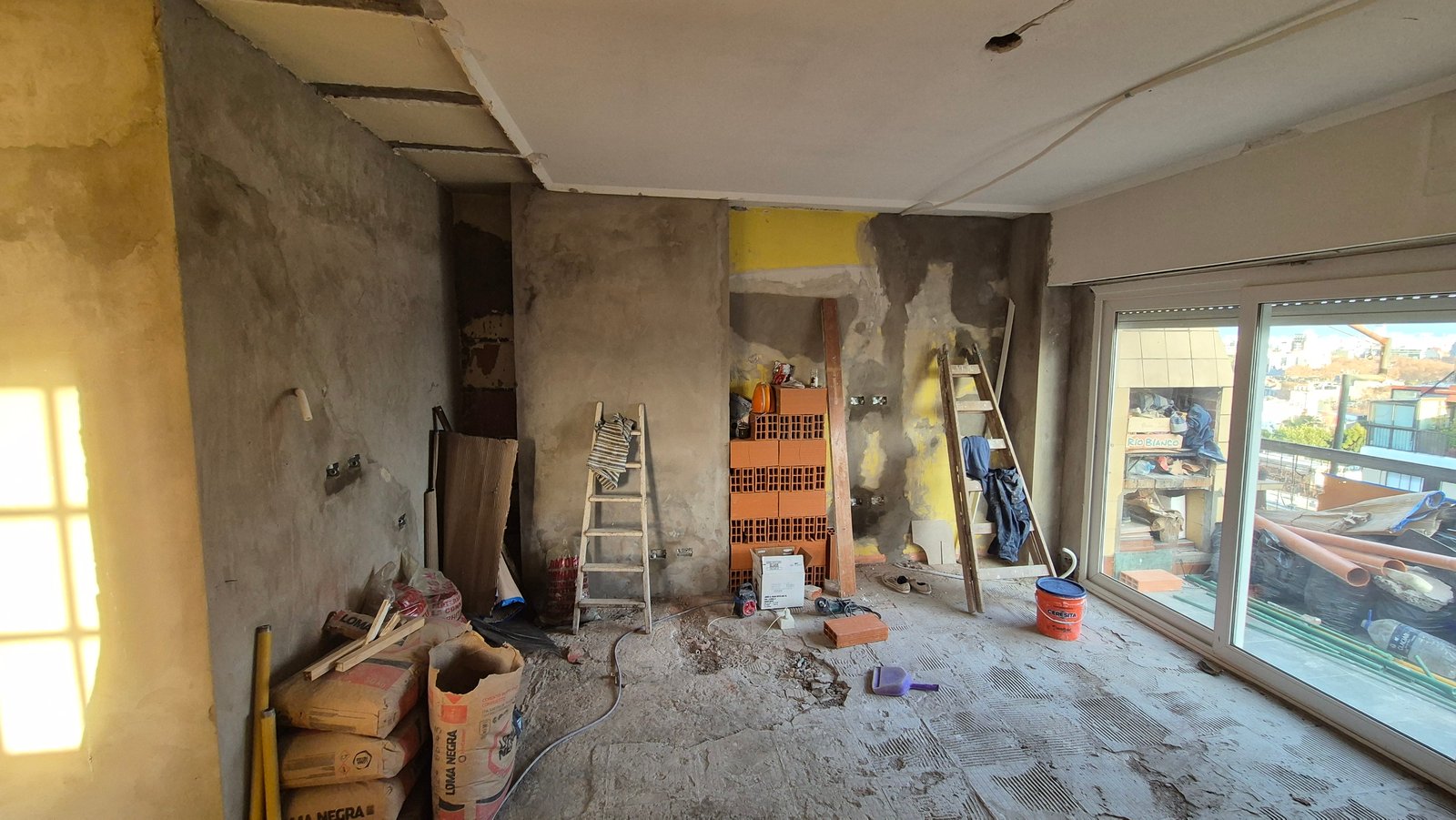 Interior en obra con paredes de hormigón y ladrillos a la vista — proyecto Living - Remodelación Soho, por RenovArqui, en Palermo