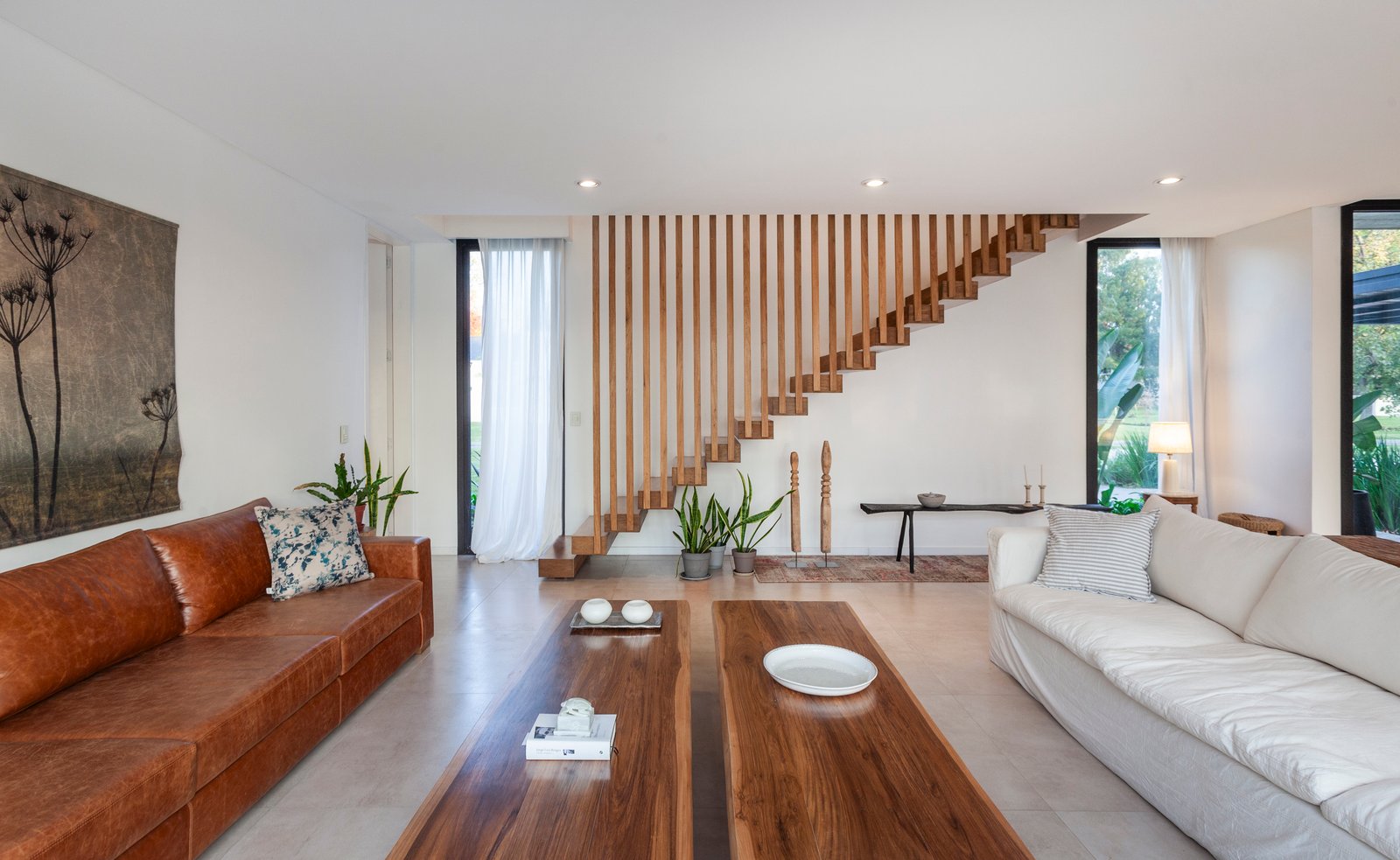 Living moderno con escalera flotante y sofá curvo — proyecto CASA HS143, por A'PRIMA - Arquitectura Sustentable, en km 7.5 Ruta 25
